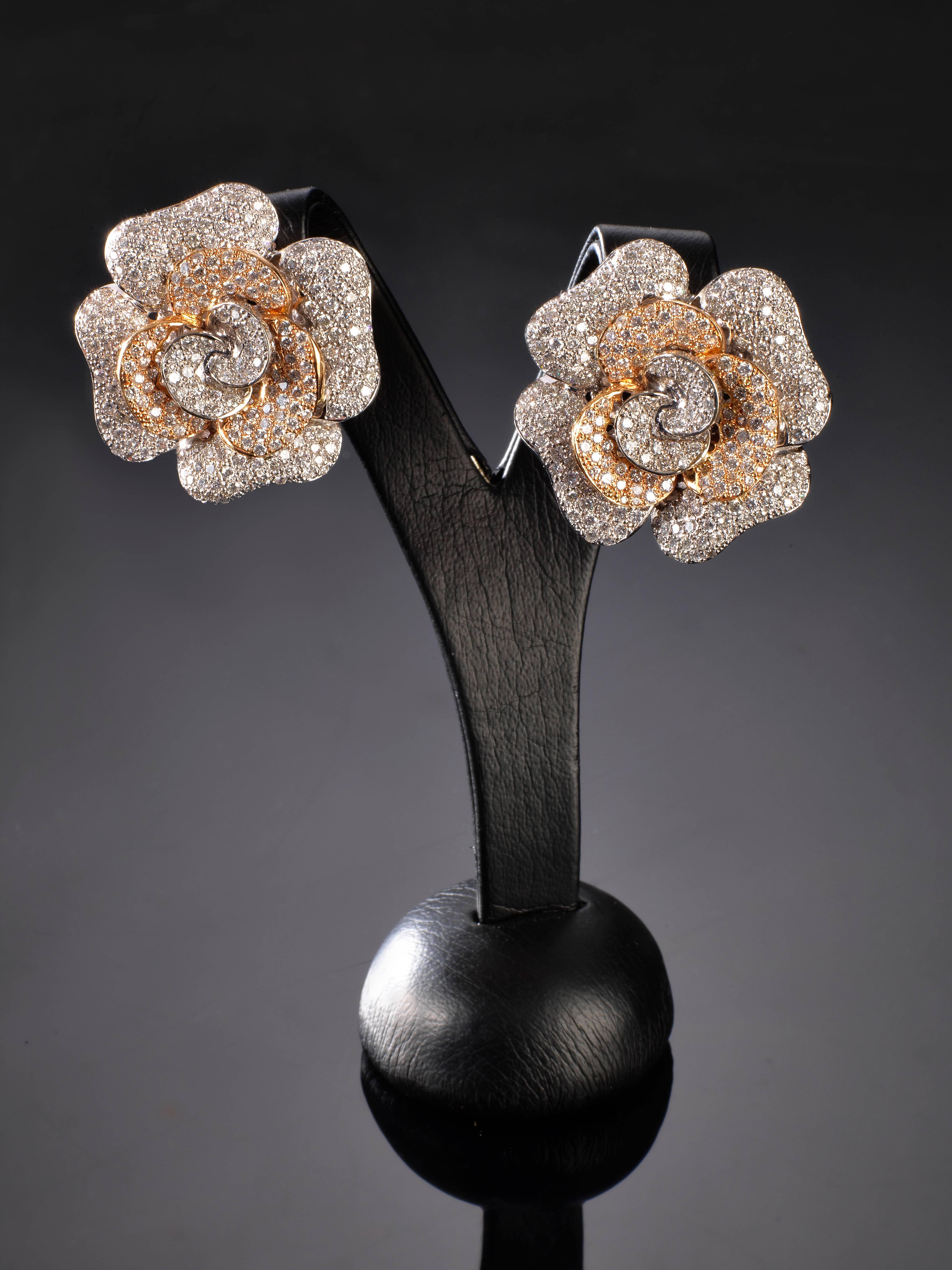 A pair of 18K white - yellow gold earrings designed as a pave set diamond flowerhead. They are Set with brilliant cut diamonds weighting 7,13ct. approximately. 

The earrings measure 2,9x2,9 mm.