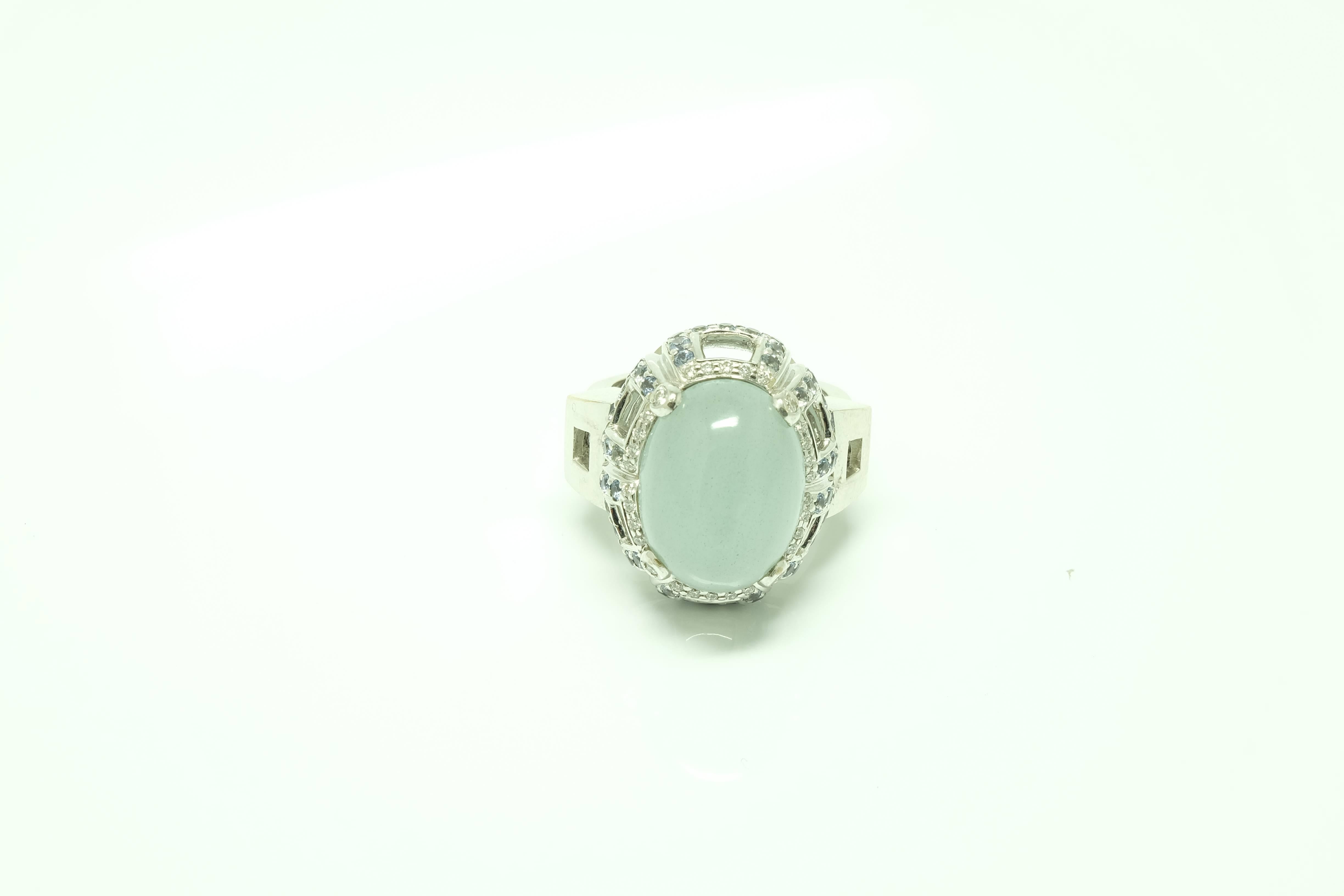 A 18 karat white gold cocktail ring with a cabochon cut Aquamarine centre stone, surrounded by brilliant cut sapphires and brilliant cut diamonds set on the claws.

Size:  14 EU   6 1/2 US 
Aquamarine measurements: 16x12mm
Internal diameter: 17