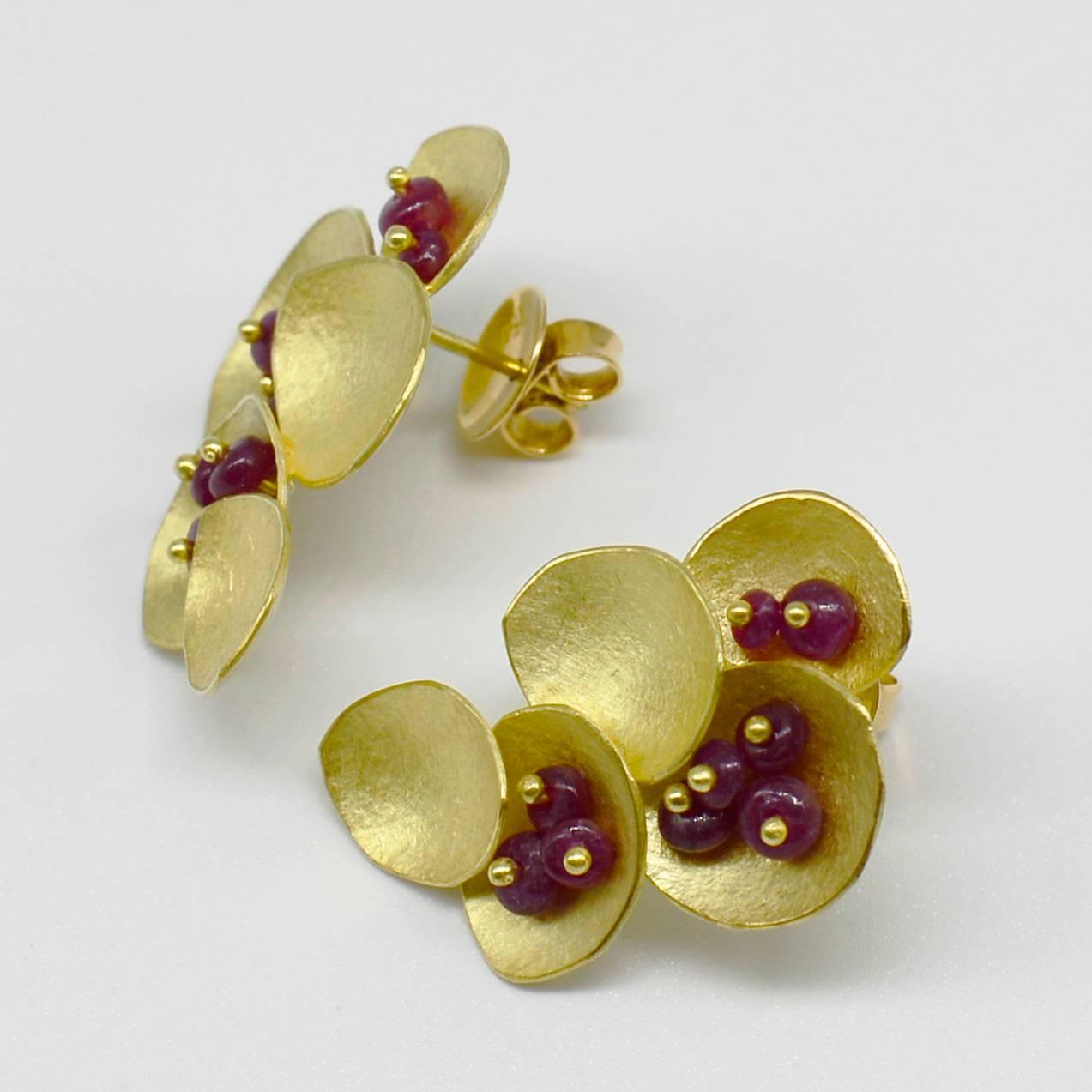 Layers of petals create rhythm and movement. Each individual 18ct gold petal is cut out and formed by Kayo Saito and her team. The ruby beads are from India and add a berry-like colour to the earrings. The petals have a delicate texture that gives a