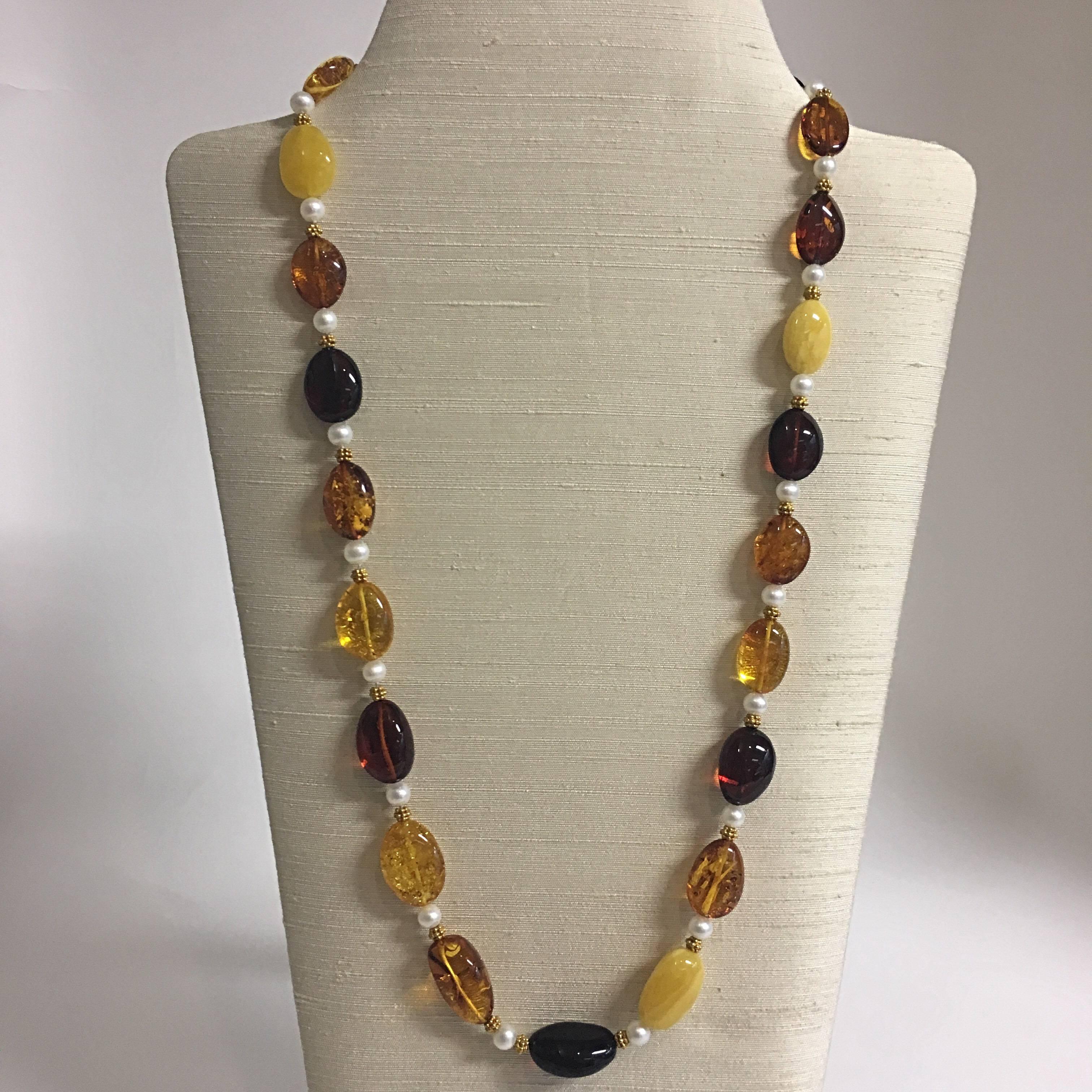An elegant  29”L (74cmL) necklace with oval Baltic amber beads, ranging from 5/8”L (1.5cmL) to 1”L (2.5cmL) in butterscotch, lemon, honey, cognac and cherry colours, 18 karat granulated gold beads, freshwater pearls, and an 18 karat clasp with