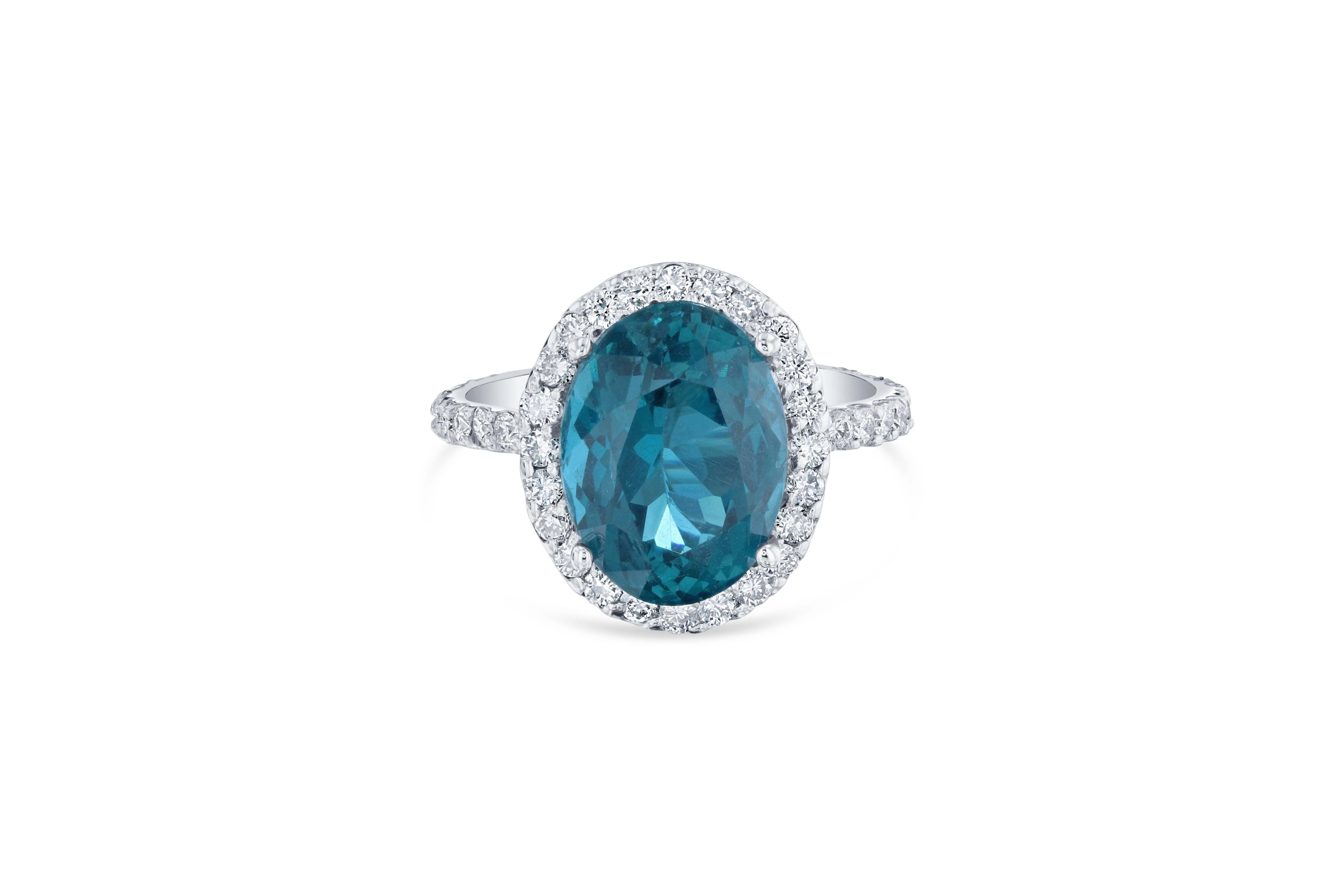 This ring has a 6.07 carat Oval Cut Apatite in the center of the ring and is surrounded by a Halo of 48 Round Cut Diamonds that weigh 0.88 carat Clarity: VS2, Color: H. 

The total carat weight of the ring is 6.95 carats. The ring is made in 14K