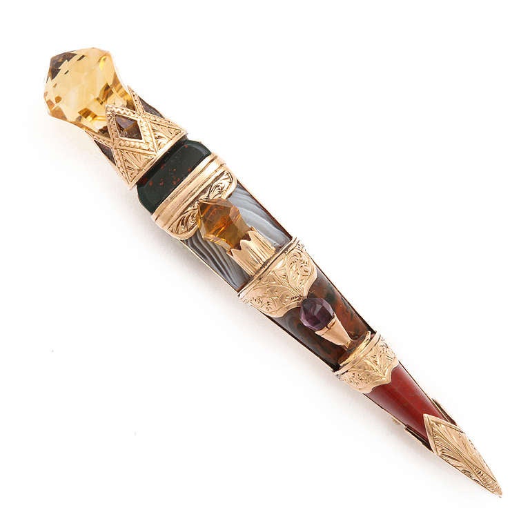 Gold-set brooch with hardstone hilt comprised of bloodstone, agate, and vari-colored jasper ornamented with two citrines and an amethyst. It is made from the handle of a sgian dubh, a dagger kept in the sock in traditional Scottish highland