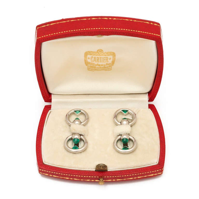 Pair of platinum stirrup double cufflinks, each link set with two sugar loaf cabochon emeralds, and two fancy triangular-cut emeralds. In Cartier box.

By Cartier, Paris