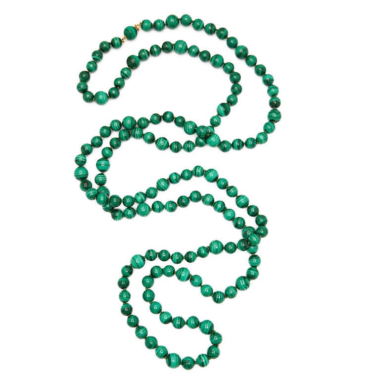 Long strand of 8 mm malachite beads, evenly interspersed with 10 mm malachite beads. Fastens with a malachite and gold bead clasp.

Beads circa 1940, contemporary mount.
