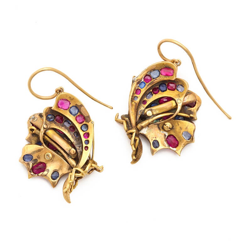 Pair of ruby, diamond, and sapphire pendant butterfly earrings poised in flight, set in gold.