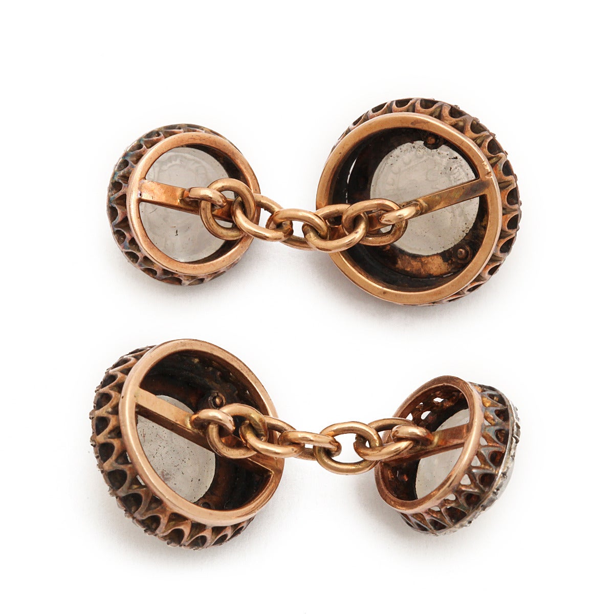 Carved mask moonstone double cufflinks with rose-cut diamond surrounds, mounted in rose gold.

English, ca. 1870.