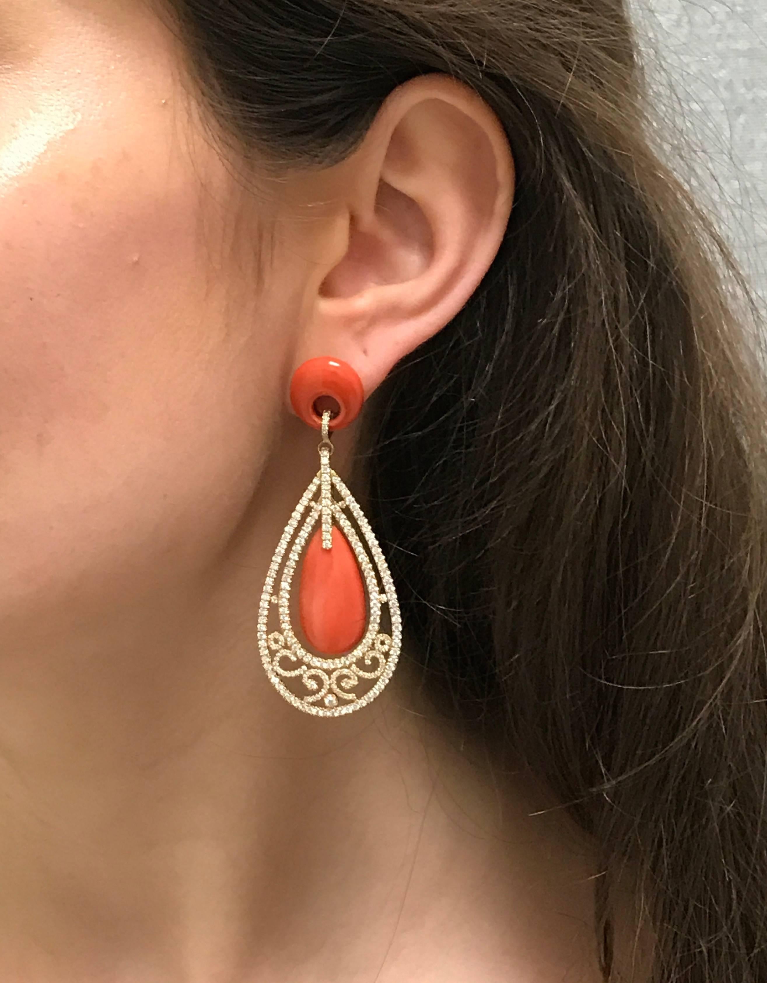 An ornate pair of chandelier earrings with beautiful natural coral. These earrings are handcrafted in 18k Yellow gold and set with 390 full cut pave set diamonds totaling 5.53 carats. Finished with a post and omega clasp mechanism for comfort and