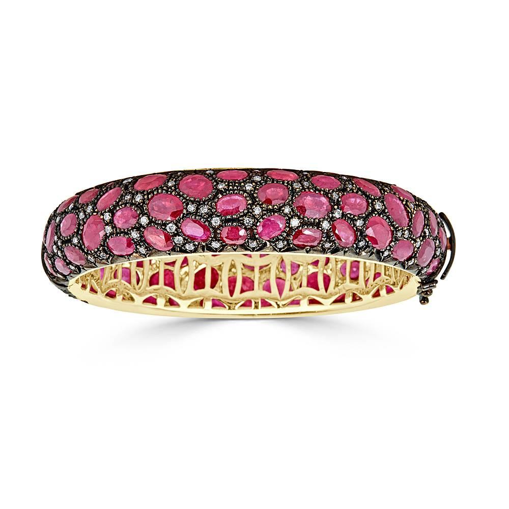 A Pave African Ruby and Diamond Bangle Bracelet in 18k White and 18k Yellow gold. This bracelet features 48.70 carats Total of African Rubies mixed in a pave setting with 2.55 carats Total of White Diamonds. The top portion of the bracelet is