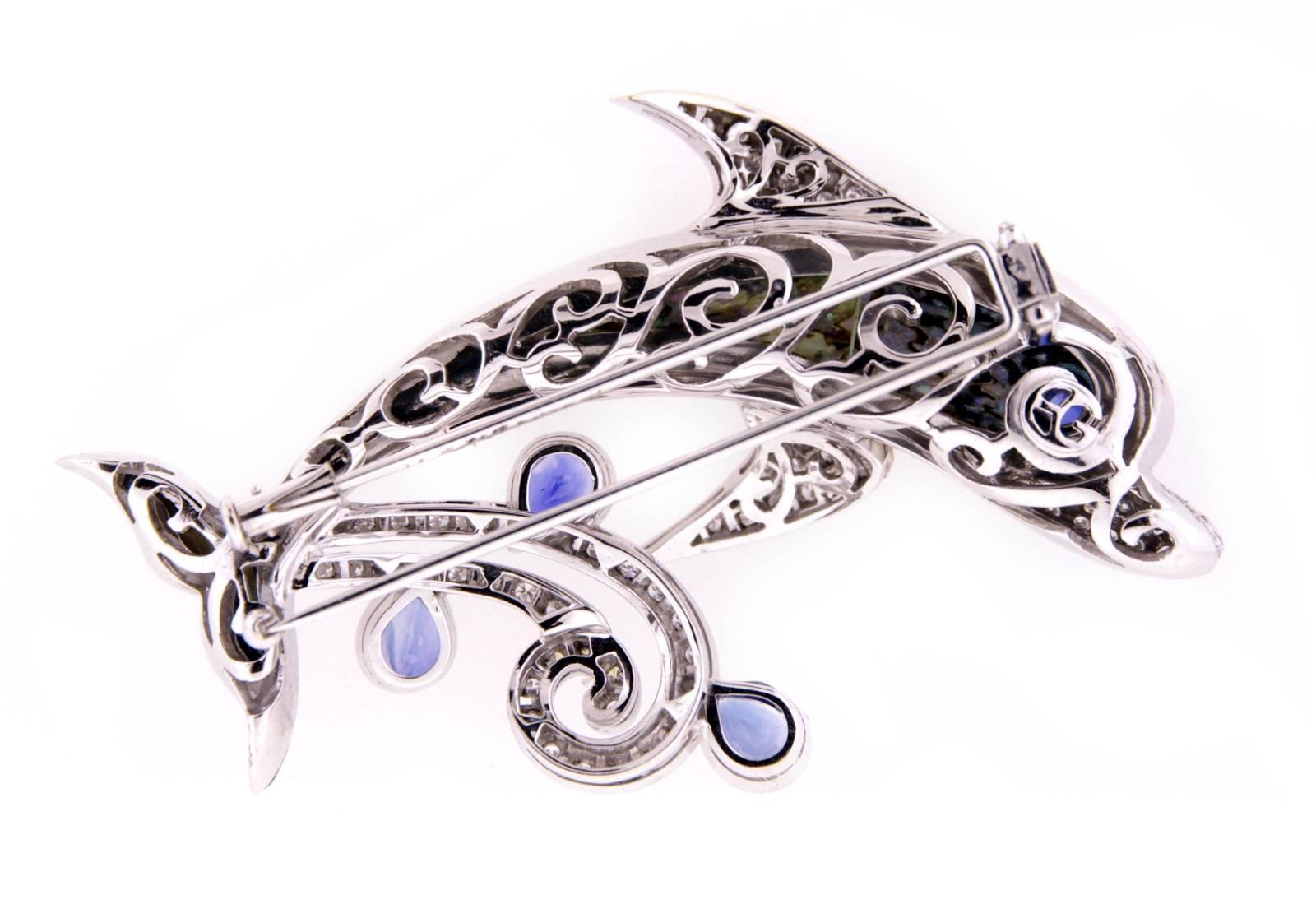 The dolphin brooch springs up from the sea and creates a diamond wave and mist with 5.56 carats of faceted blue Ceylon sapphire. The three-dimensional body is decorated with tinted New Zealand paua shell (abalone) topped by transparent crystal,