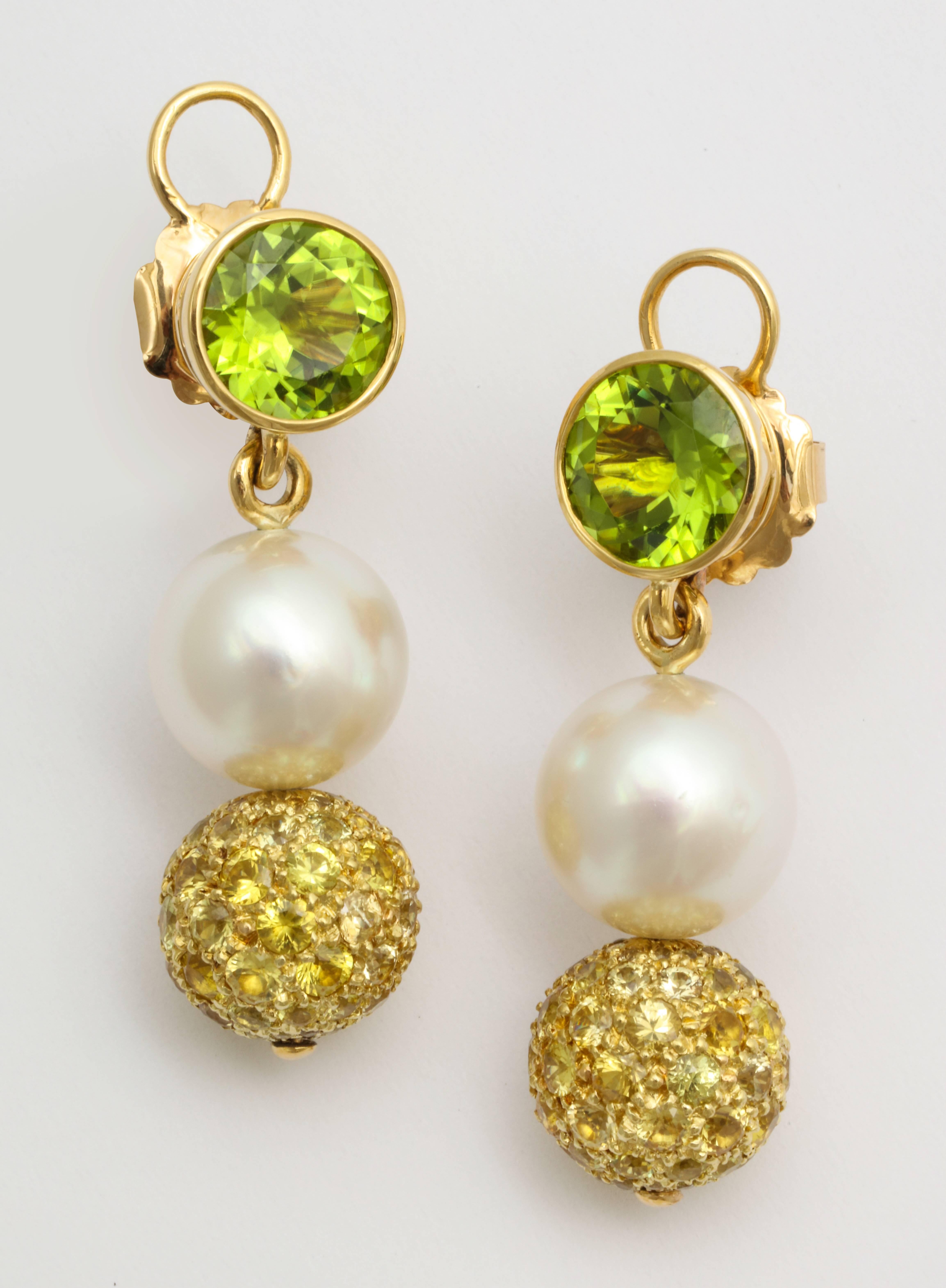 A pair of 18 karat yellow gold earrings with South Sea pearls, yellow sapphires, and peridot. The South Sea pearls measure at 11.5 and 11.6mm. The round brilliant cut peridots have a total weight of 5.32 carats. The pavé set yellow sapphires have a