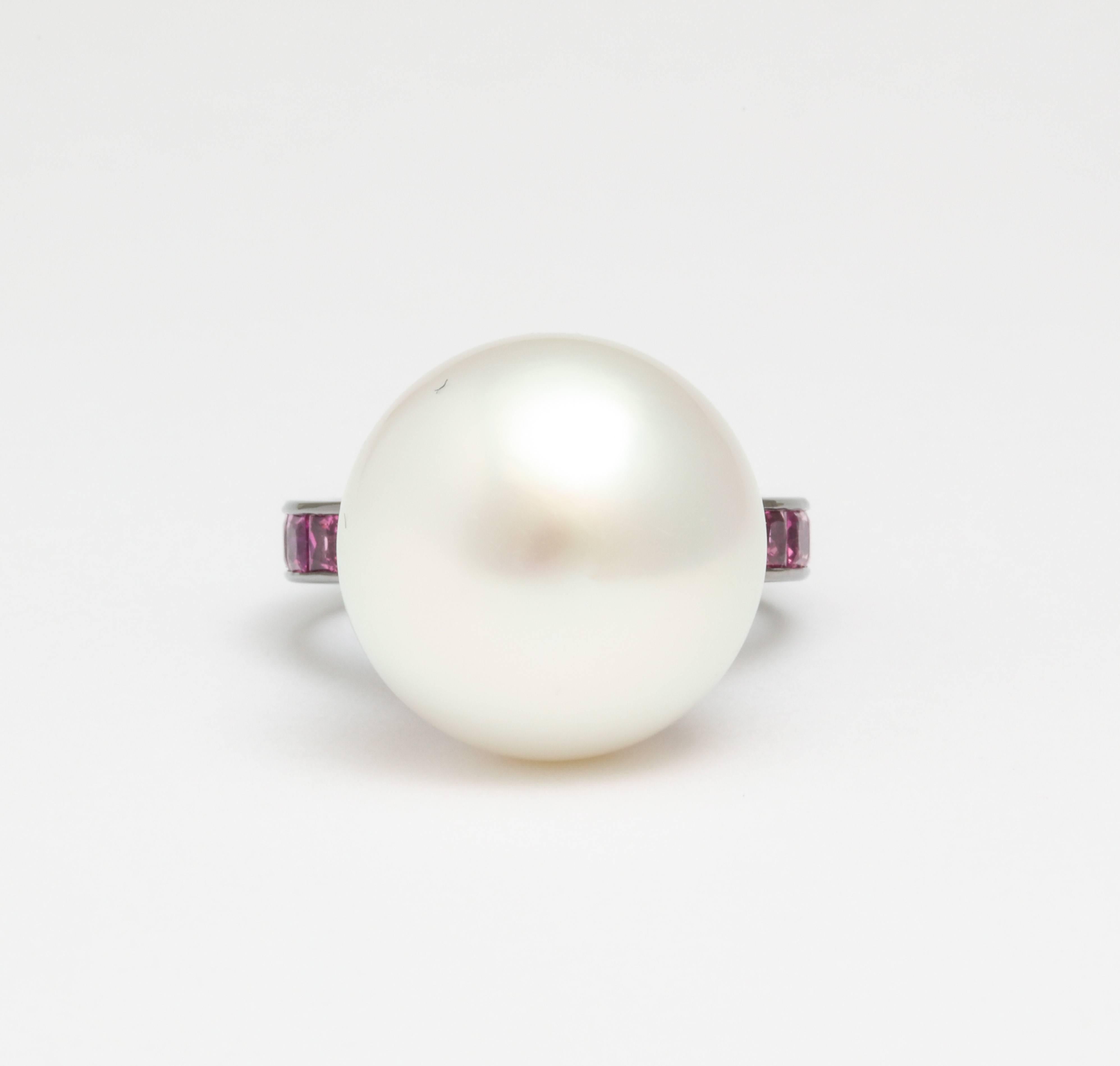 A ring set in 18 karat white gold with black rhodium featuring an exceptional 30.99 carat South Sea pearl. The pearl measures 16.8 x 15.2mm and weighs 1.64 momme. There are 14 princess cut hot pink sapphires on the band, weighing a total of 2.73