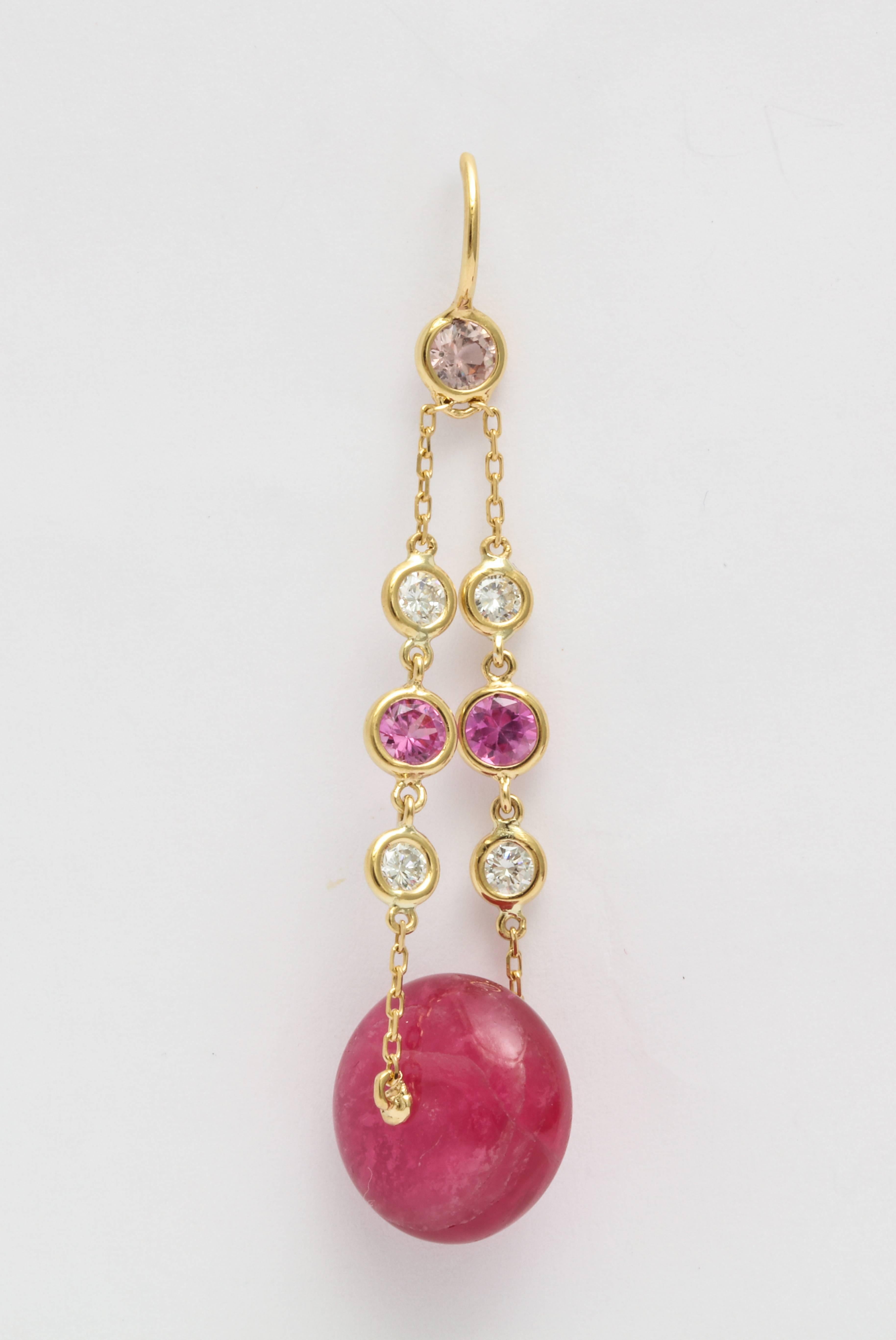 A pair of earrings featuring two large, pink tourmaline beads with a total weight of 22.84 carats. They are suspended from 18 karat yellow gold chain and accented with round pink sapphires and round white brilliant diamonds. The total sapphire