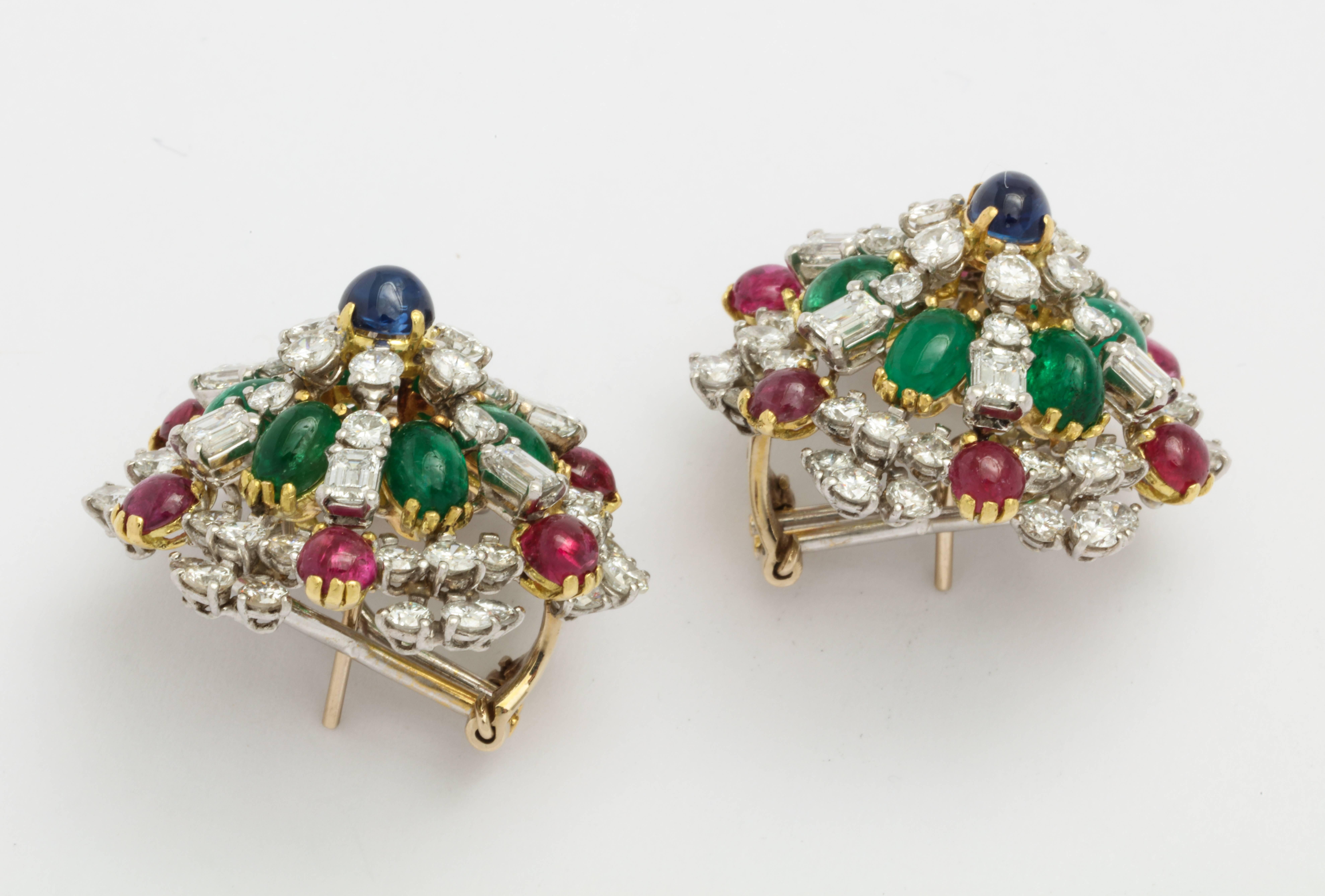An impressive pair of clip on earrings featuring cabochon rubies, sapphires and emeralds and both round brilliant and emerald cut diamonds. Set in platinum and 18 karat yellow gold. Circa 1960s, with French import and export marks. 
Rubies: 4.08