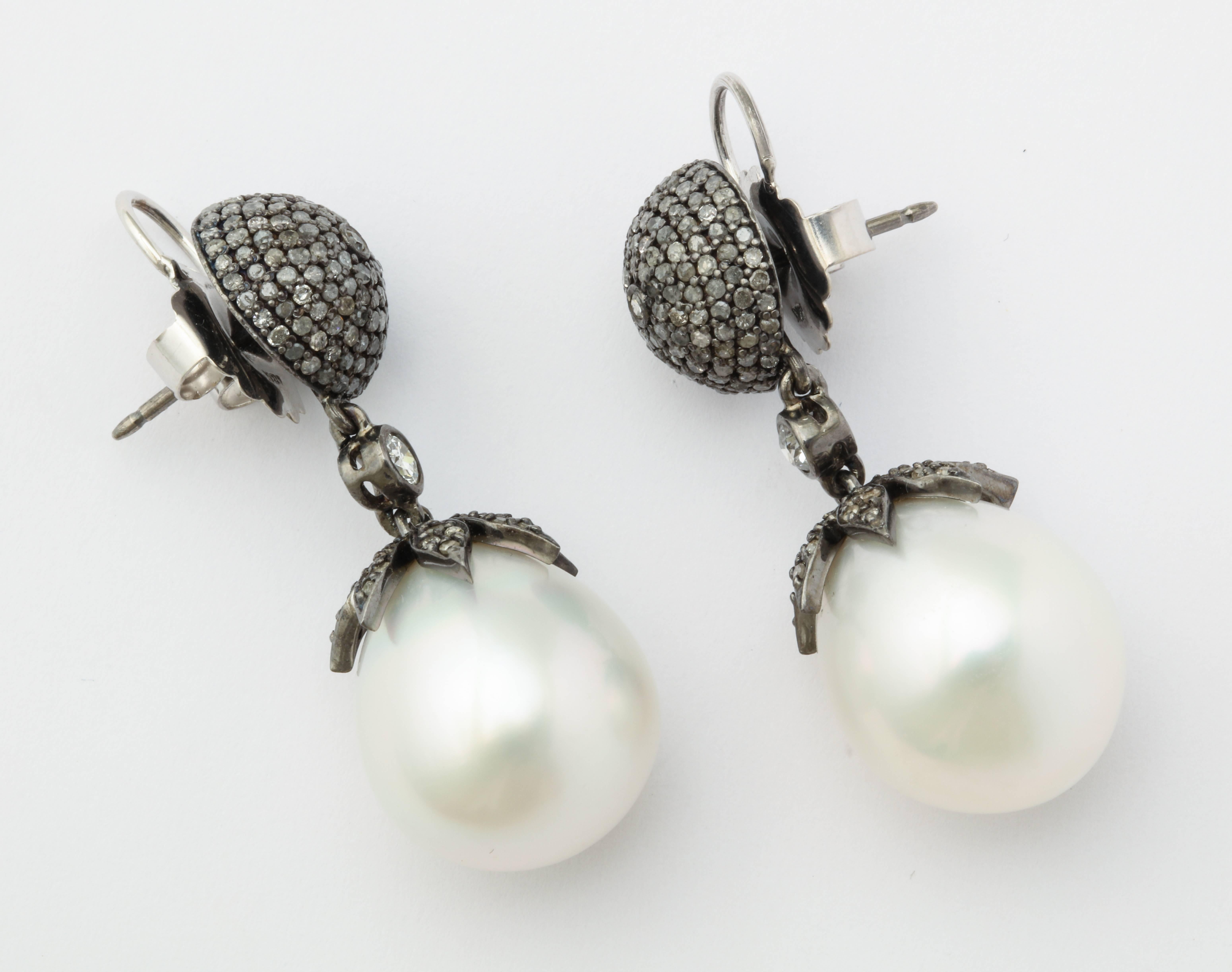 A smart day into night earring featuring bright white, high luster south sea cultured pearl drops suspended from a dramatic grey and white diamond button created with antiqued silver finish cap and 18K WG friction backs and posts.
