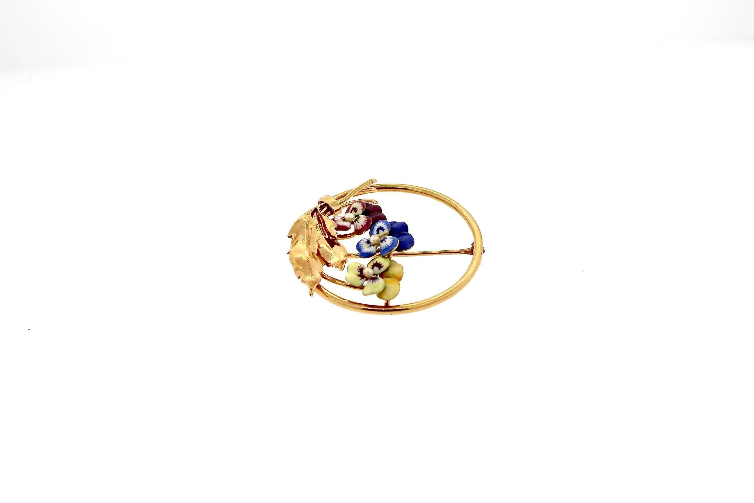 An  circular brooch that is accented by brightly colored enamel pansies.  This pin was made in the early 20th Century, around 1940.  It is made in 14k gold, typical of American jewelry at the time.  It was likely made by the manufacturers in the