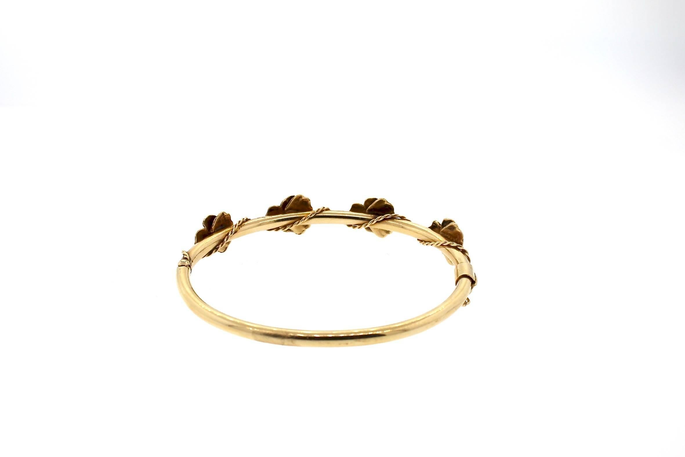 Four gold purple enamel pansy flowers set with diamonds in the center are set on top of this 14k yellow gold hollow bangle for a feminine look.  A thin twisted wire of gold accents the design.  This bracelet is perfect on its own, or stacked with