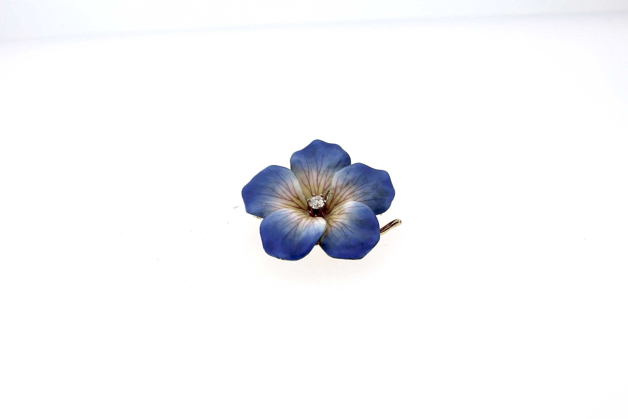 A vibrant blue colored enamel periwinkle flower brooch set with a round diamond in the center. The tips of the blue petals are delicate and detailed. The brooch was made around 1950 and made in 14k yellow gold. There is a pin stem and a loop to wear