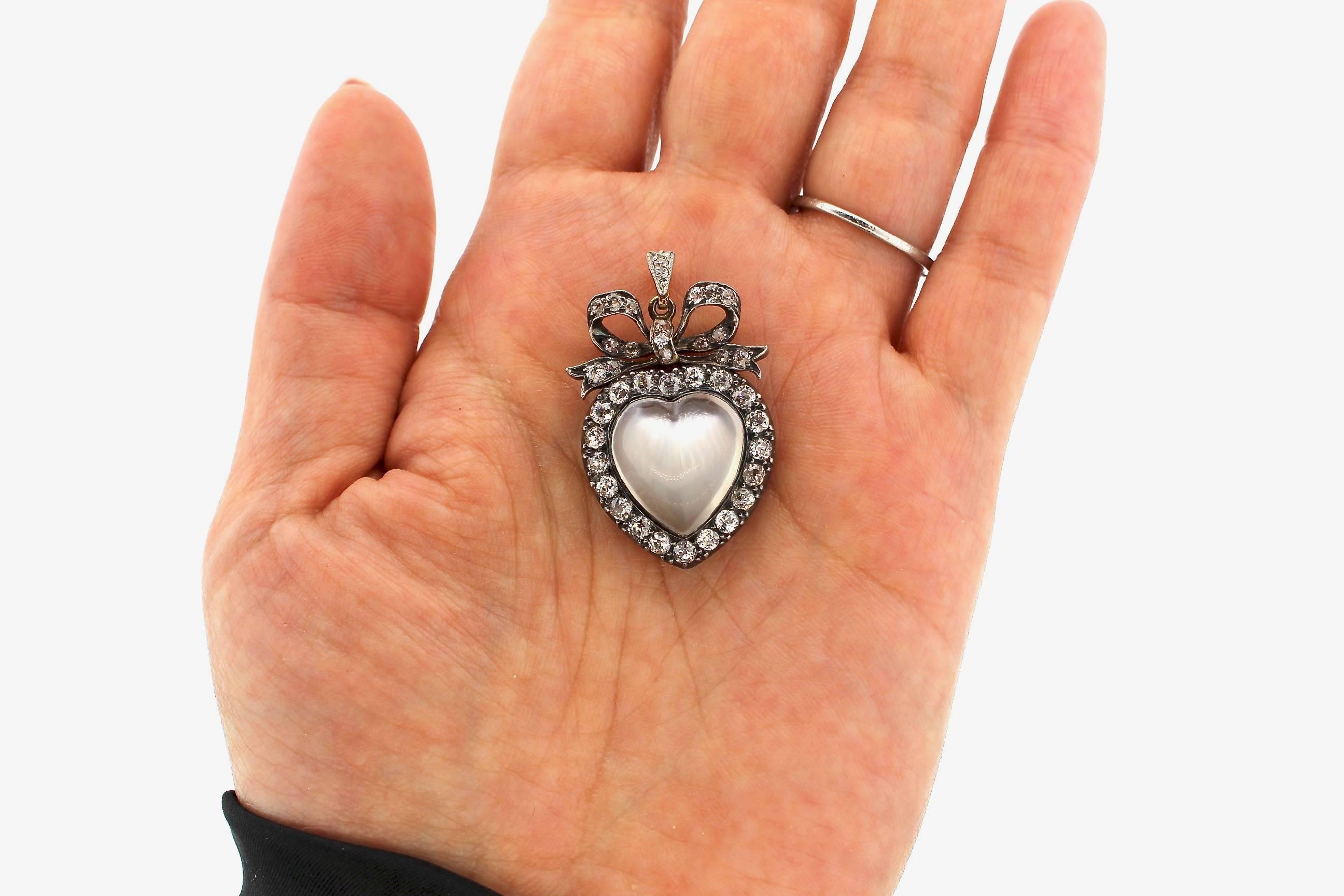 A sentimental 19th Century diamond and moonstone heart pendant set in silver topped gold.  The large luminous heart shaped moonstone is surrounded by old mine cut diamonds.  There are 35 diamonds weighing a total of approximately 2.65 cts of