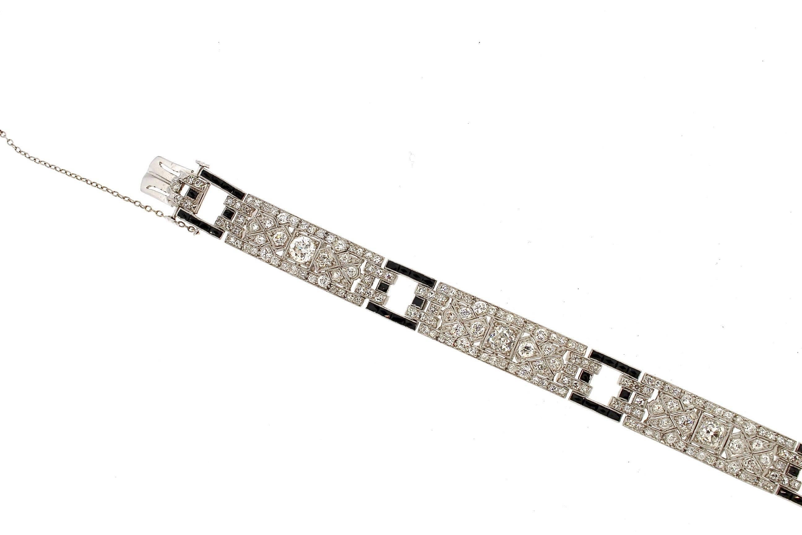 Bracelet Art Déco en platine, facile à porter, en diamants et onyx, vers 1925.  De jolis onyx taillés à la française créent des liens carrés ouverts qui relient trois panneaux identiques de diamants.  Il est beau tout seul ou peut être porté avec
