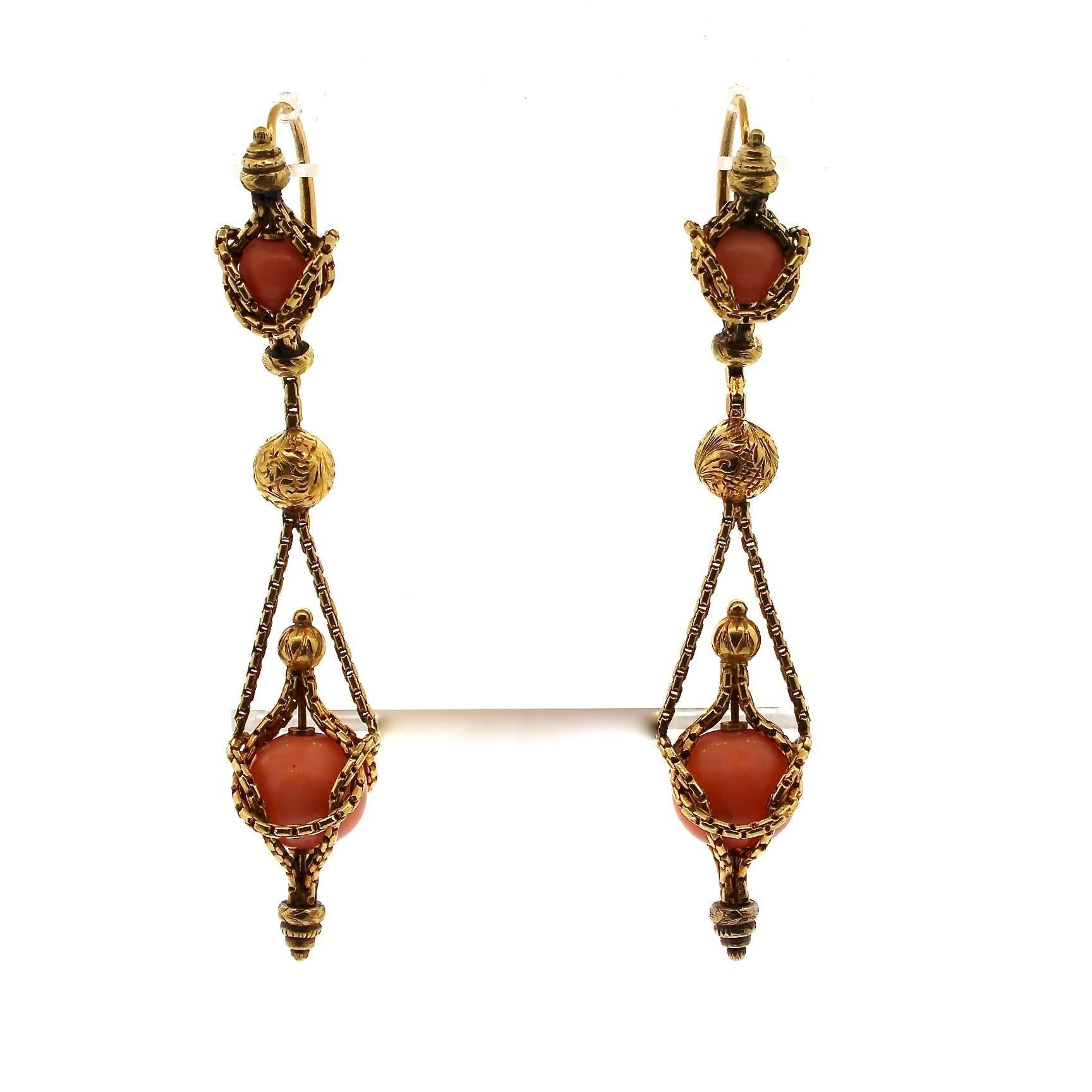 This is a gorgeous dramatic pair of Victorian Etruscan Revival coral dangling earrings.  The earring is composed almost like hanging urns, but with fine gold cord suspending coral beads.  The earring is made in 18k gold and has a front to back