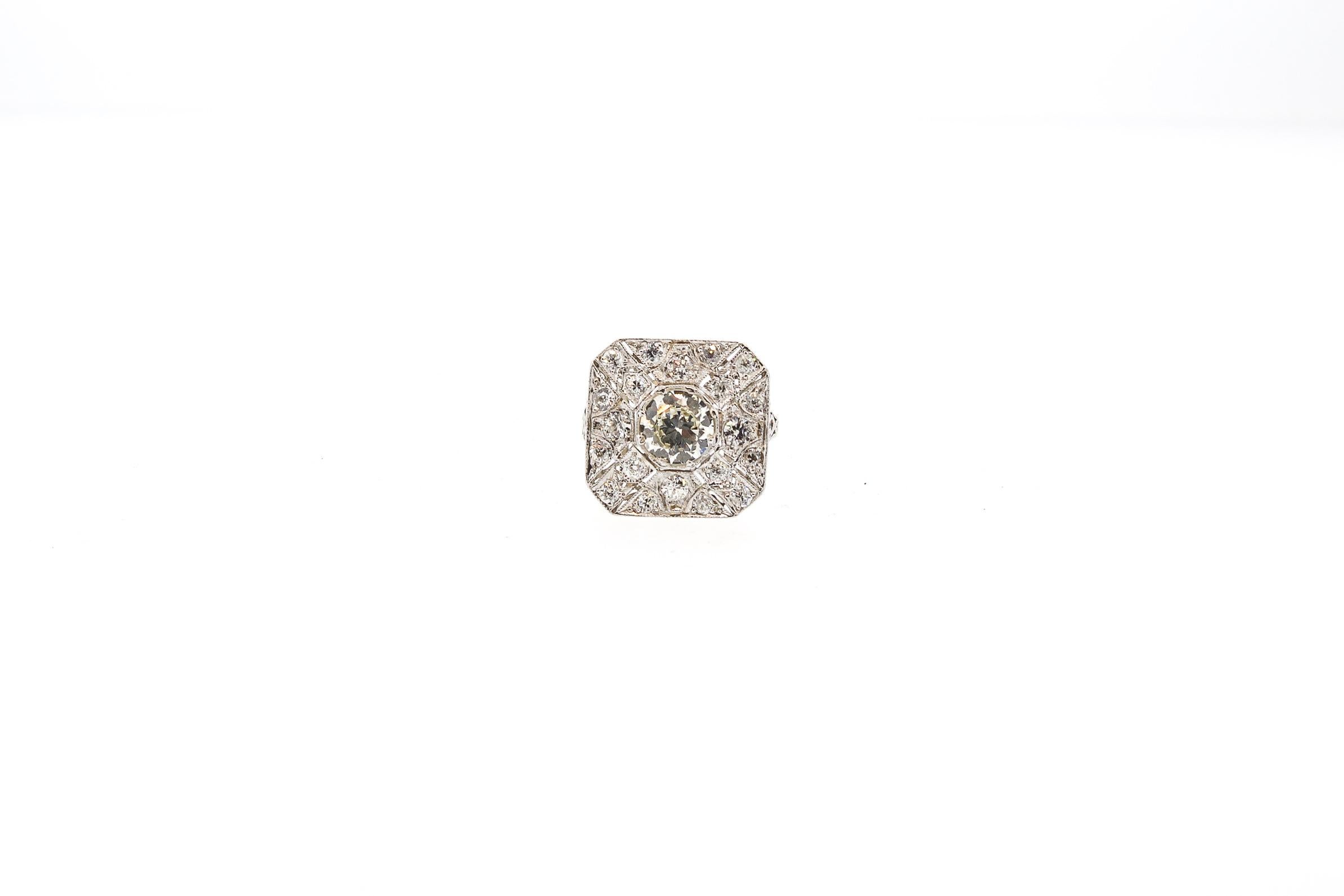 Delicately detailed Edwardian platinum diamond filigree ring centering on a center Old European cut diamond weighing approximately 1.25 cts. The central diamond is set in a finely crafted filigree panel that creates almost a target pattern. The ring