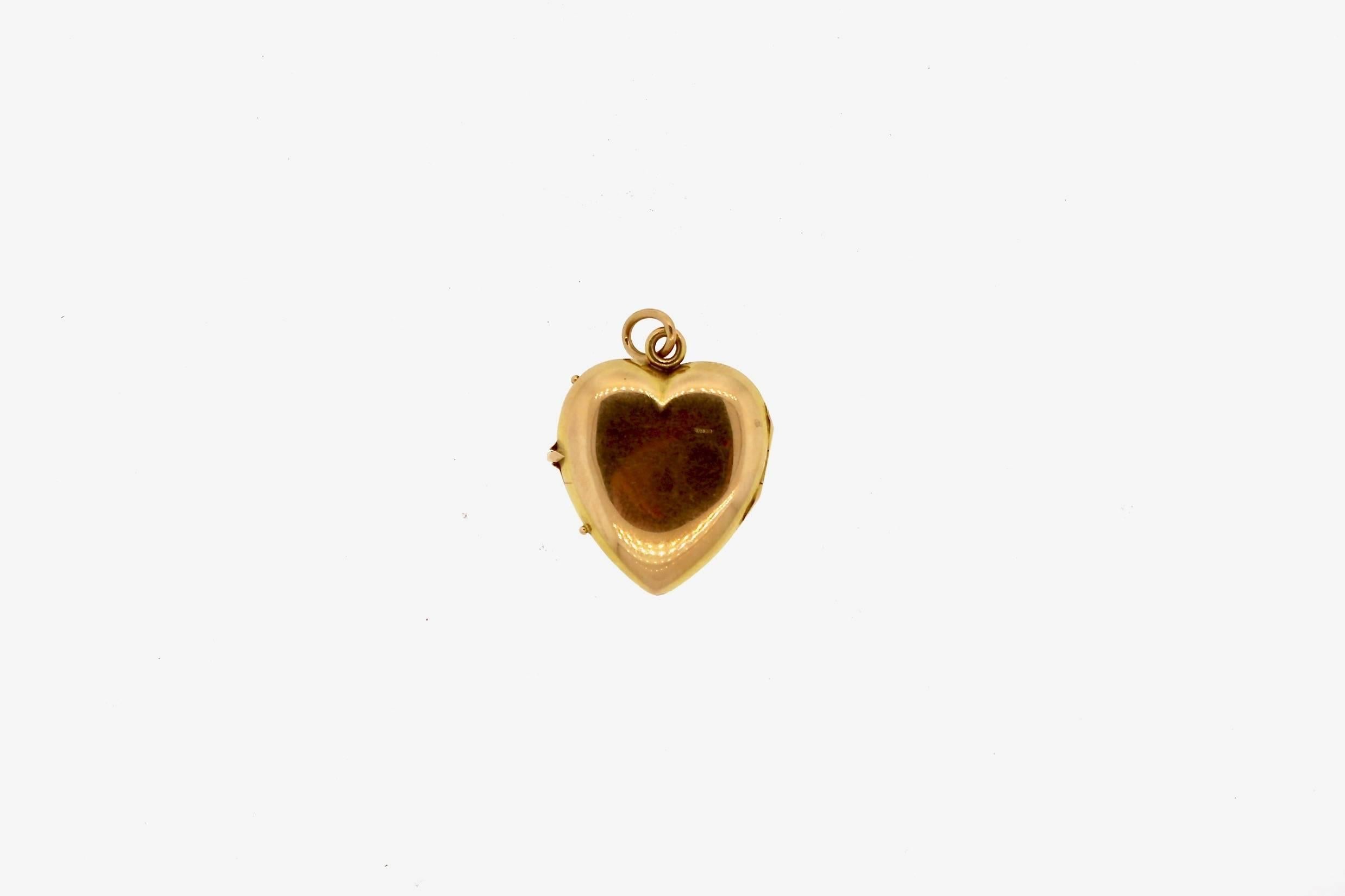 A sweet and sentimental heart locket pendant with a painted purple and yellow pansy on the front.  The locket opens and can hold photographs.  The locket is made in 14k gold and likely made in the United States.  
