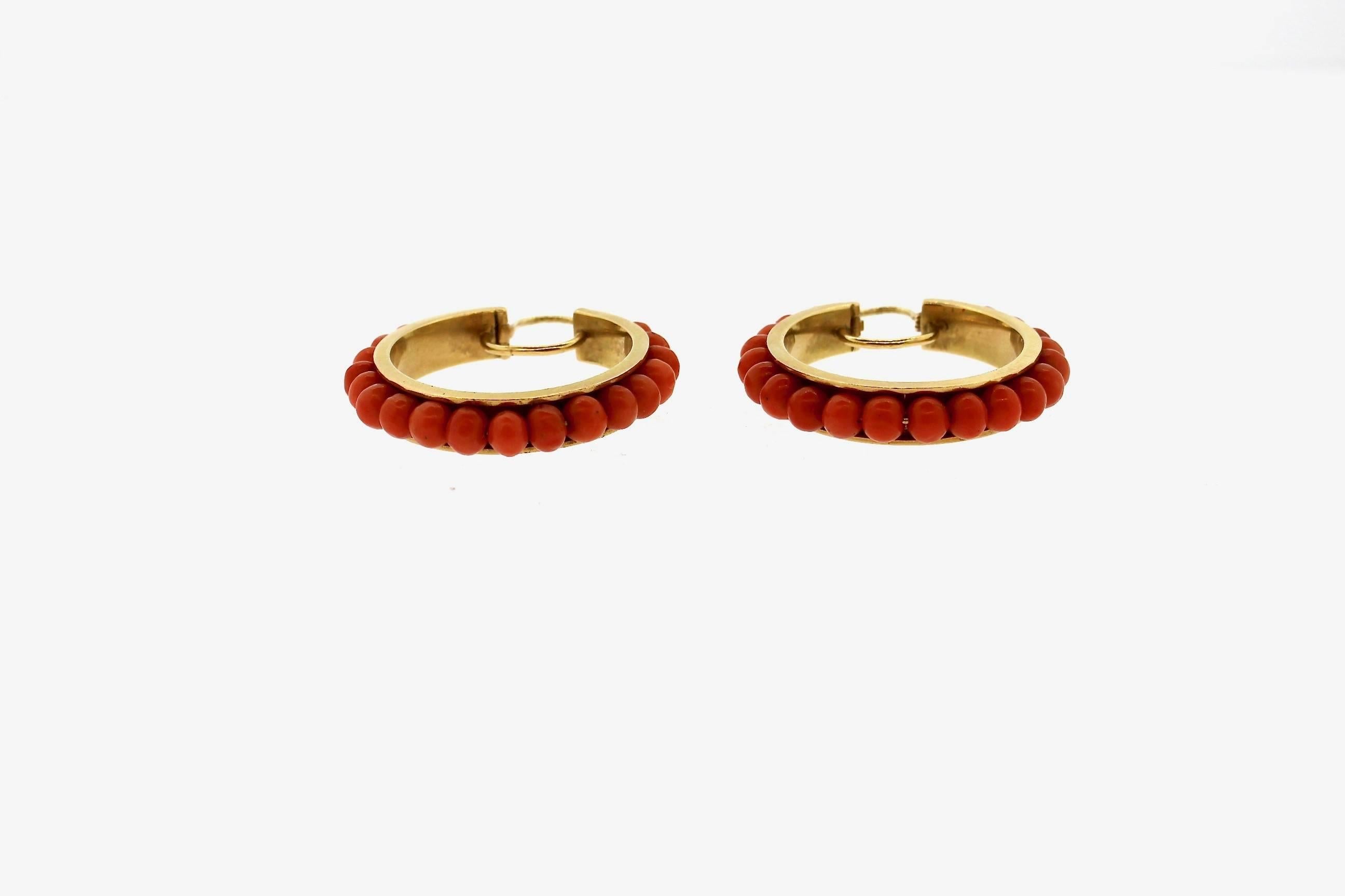 The bright color of coral make these hoop earrings pop.  This fun creole style coral bead hoop earrings date to about the 1960s.  They coral beads are strung along a wire, and channel set in the 18k gold.  This earring is effortlessly chic and