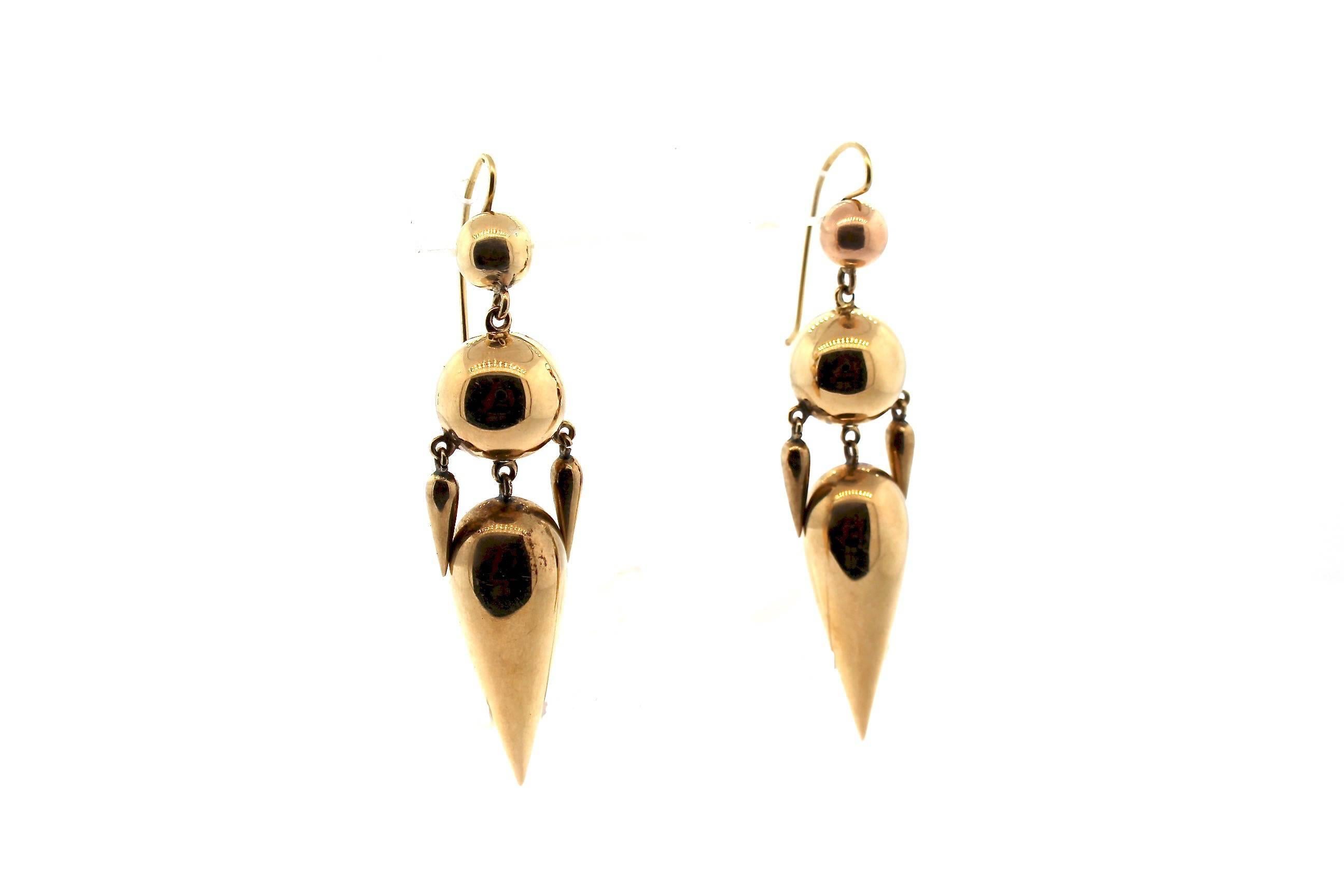 A lovely pair of Victorian hollow form 14k gold dart pendant earrings with movement and grace.  The earrings date to about 1880, and are two hollow gold balls suspending a large hollow dart shape and two smaller accents darts.  The pieces are