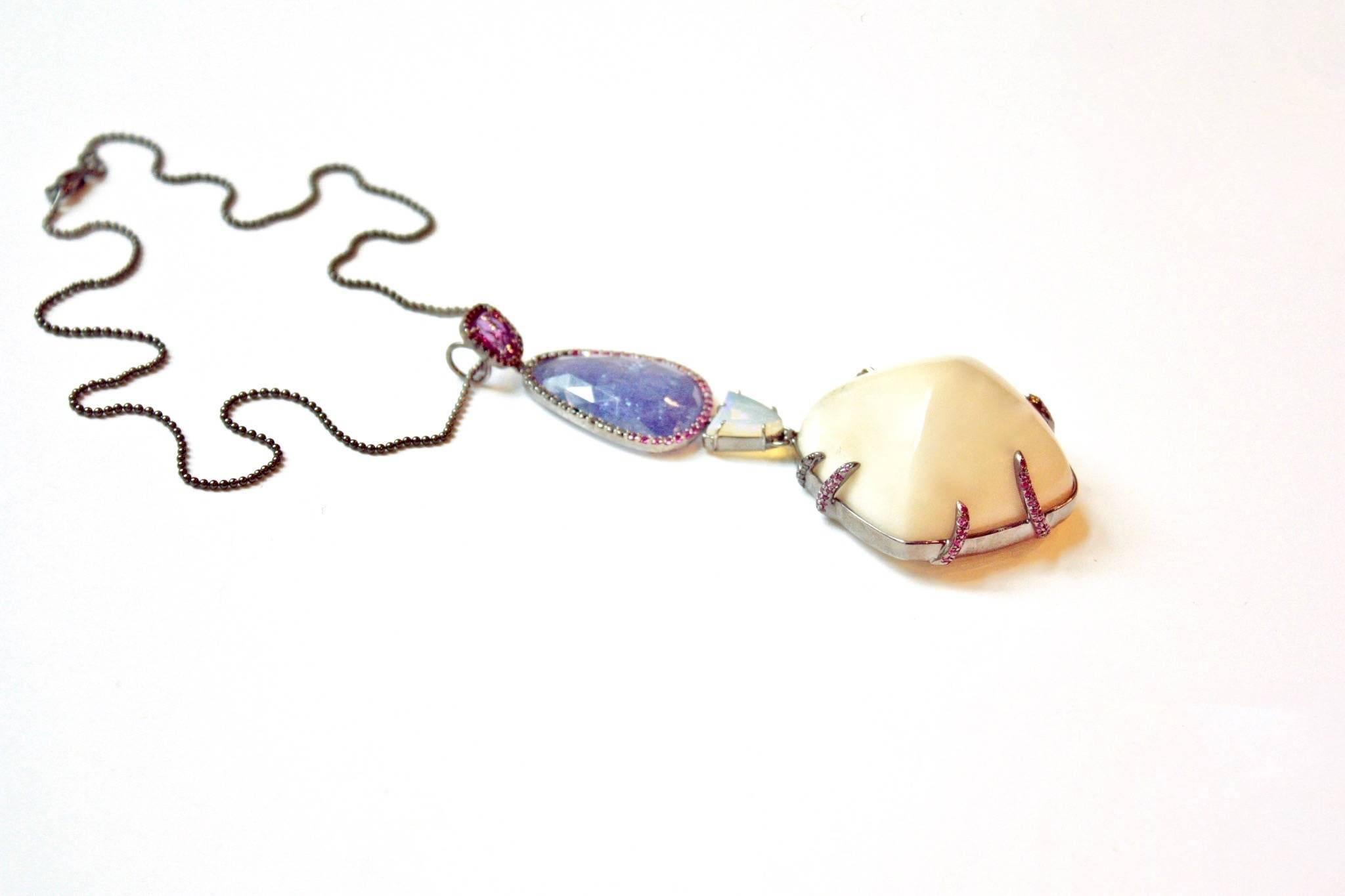 Ellie Necklace
A lavaliere necklace, created to celebrate a large sugar-loaf tagua nut.  The four organically shaped motifs begin with a pink sapphire in a black diamond surround, followed by a rose-cut tanzanite framed in pink sapphires and black