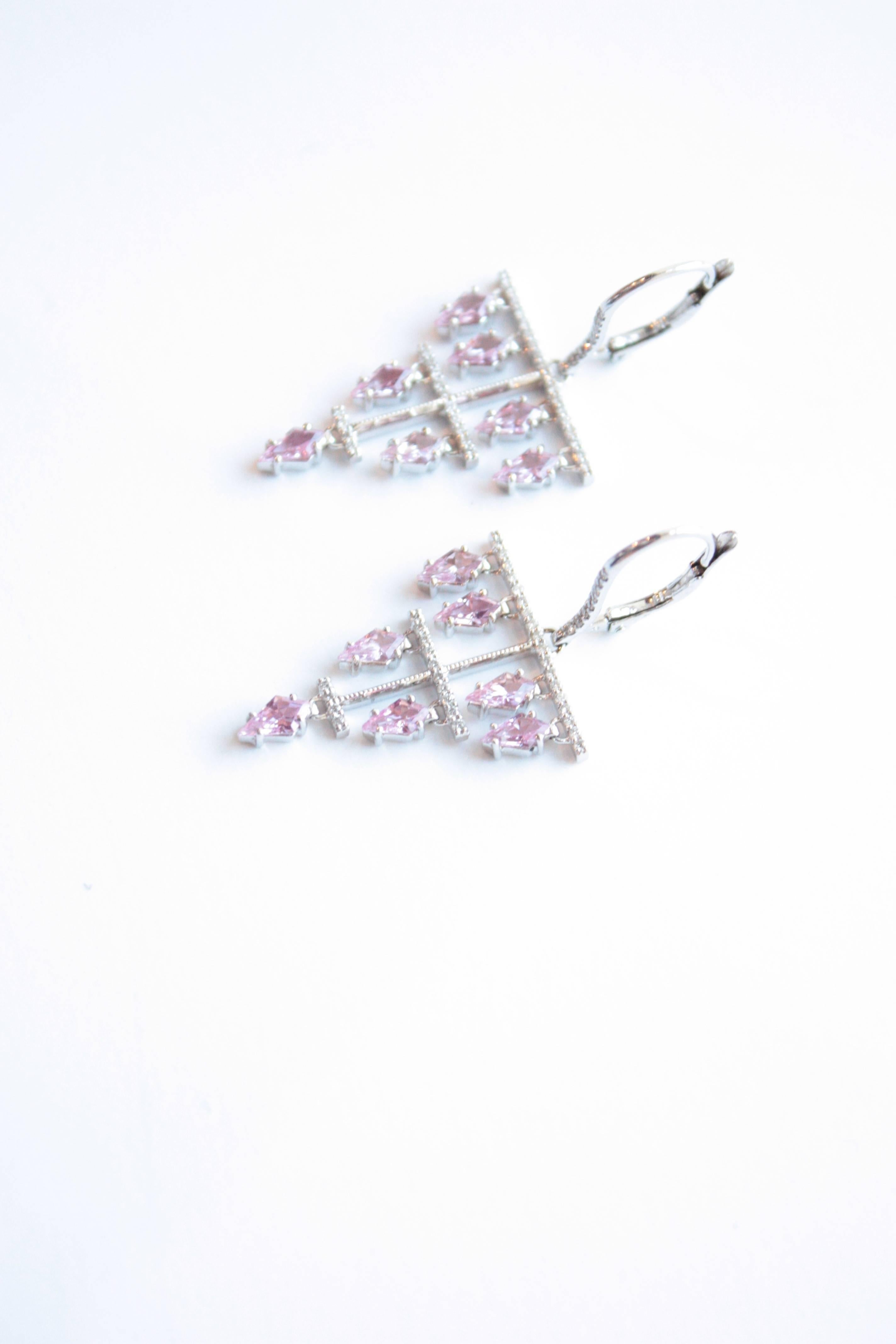 Dora Eardrops
A pair of eighteen-karat white gold fluid eardrops, each suspending seven diamond-shaped pink sapphires.  The overall contour of this earring was meant to connect with the shape of each individual pink sapphire. 
Diamond Total Weight –