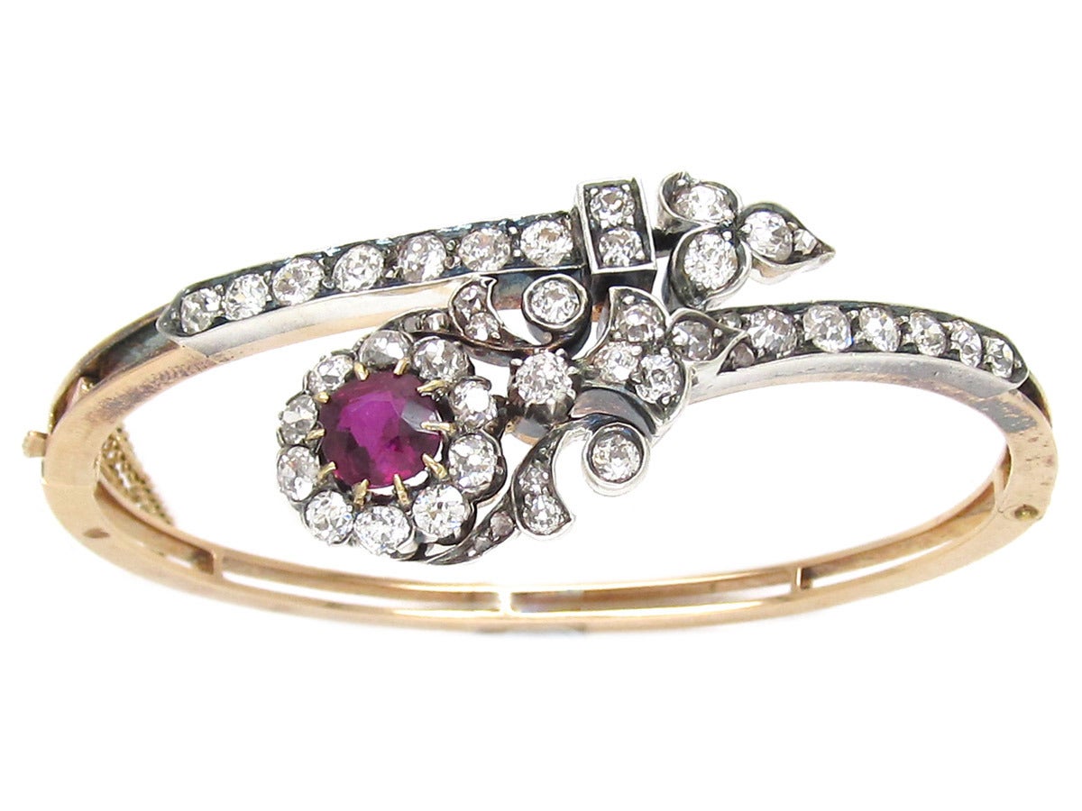 A wonderful example of the best Edwardian jewellery. This 15ct gold bangle is beautifully made with a large 1 ½ carat ruby which is surrounded by good white old mine cut diamonds. This is set off with two sections studded with more diamonds. It is a