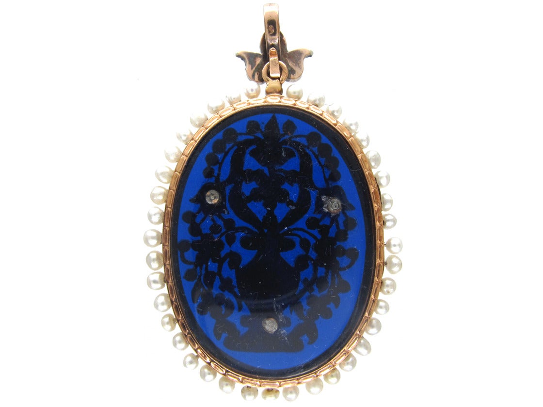 An 18kt gold French, early 19th Century pendant, set with natural pearls onto blue glass with a flower basket motif. It is an impressive piece of jewellery, very well made and unusual.