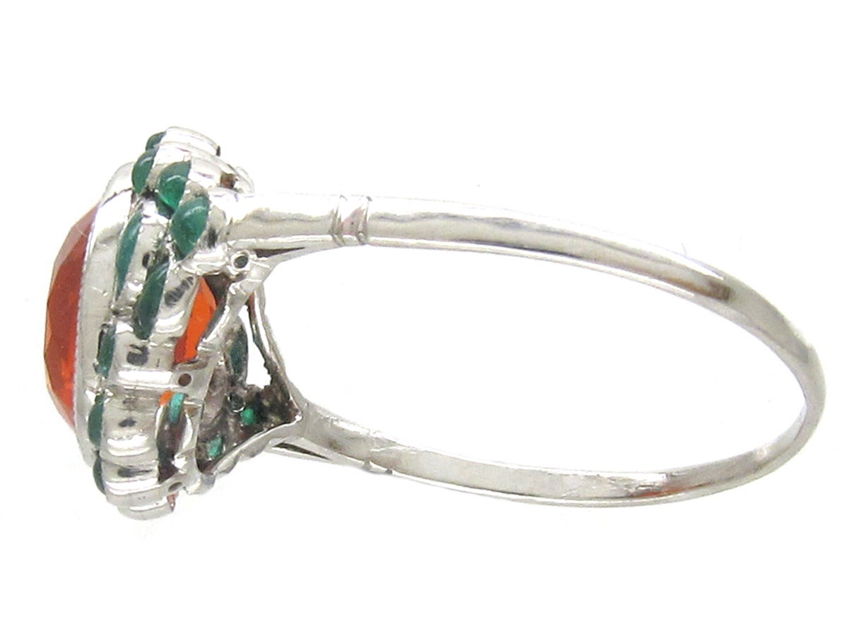 A fine quality, oval fire opal and cabochon emerald ring, the likes of which rarely appear. Made circa 1910-20, the orange and green make a stunning contrast. The shank is platinum and the settings for the opal and 18 small emeralds are very finely