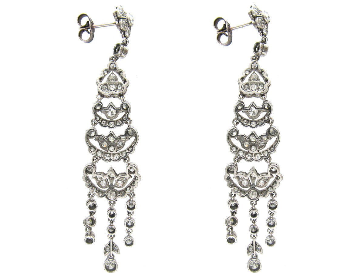 A pair of Edwardian articulated diamond earrings, mounted in platinum and made around 1915. Four decorative motifs fall one after another and are finished by three drops on each earring. They look fantastic on and would be particularly good with a