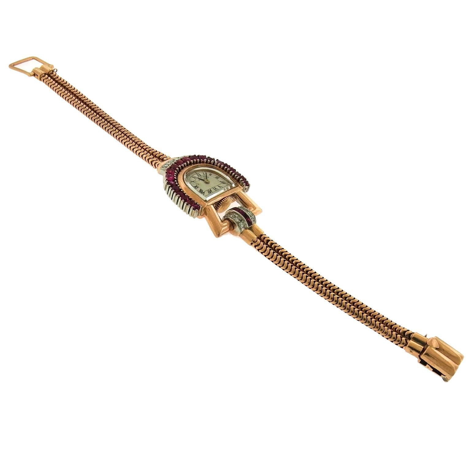 18K pink gold, ruby and diamond asymmetrical Swiss wristwatch in stirrup-style is wonderfully stylized example of the Retro-Modern movement, circa 1940's,  influenced by Art Deco and industrial design.  The overall case measures 27mm x 36mm, the