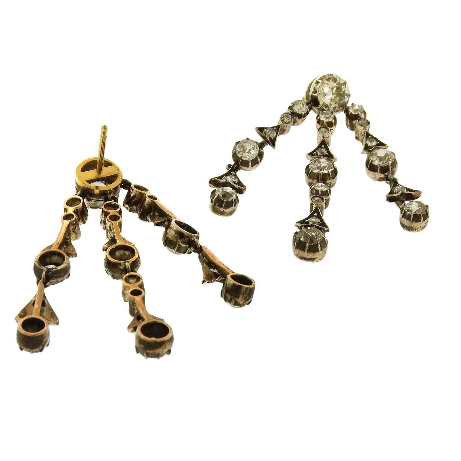 Antique Edwardian diamond drop earrings are set with approx. 7.50 carats diamonds in silver-topped gold alternating round and triangular segments, gold posts. Earrings measure 1-1/2