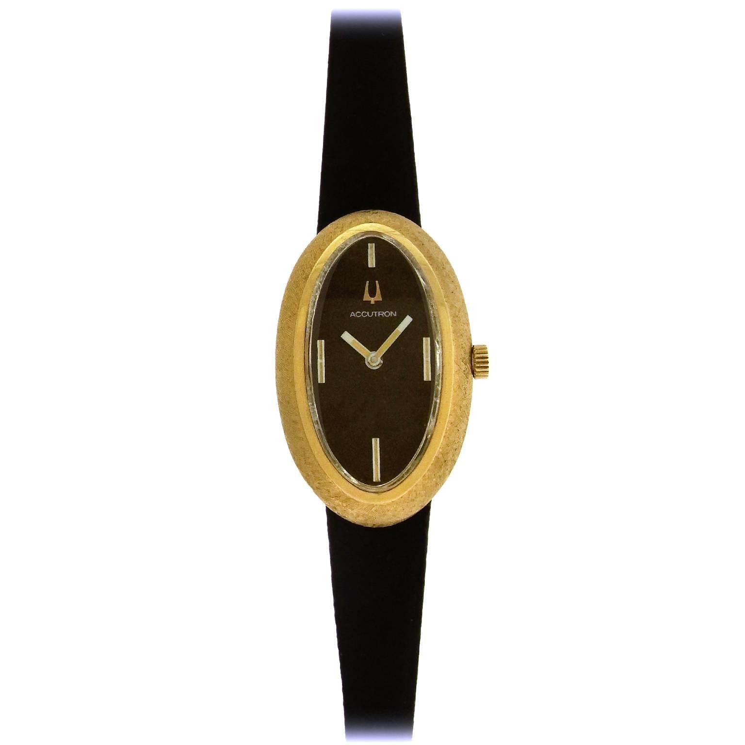 Rare 14K yellow gold women's Bulova Accutron oval wristwatch, made in 1973, features an original Florentine finish oval 23mm x 37mm case with hooded lugs, black dial with white luminous exaggerated hour indexes and white luminous hands,  the