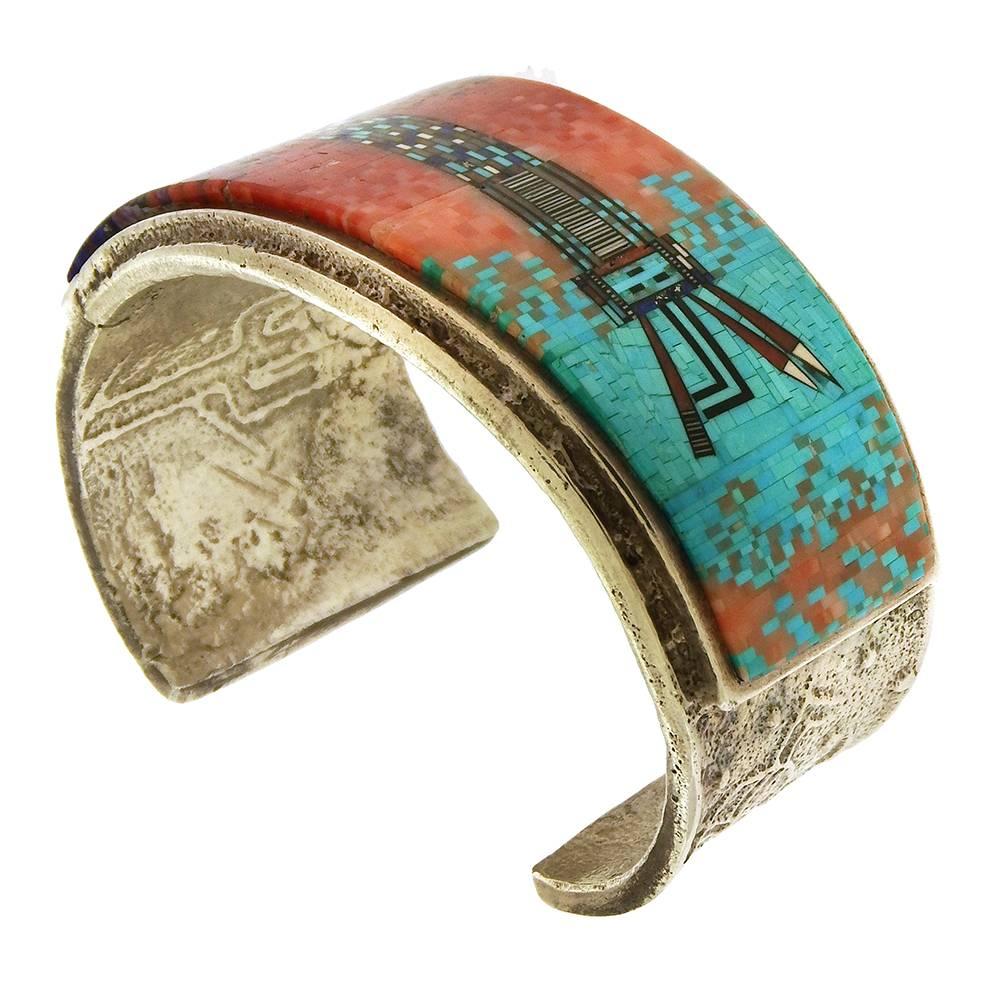 Extraordinary mosaic inlay bracelet by Irene and Carl Clark, circa 2000, is titled 'Yei", the figure depicted of the Navajo healing spirit composed of thousand of tiny gemstone tiles, including turquoise, coral, lapis, sugilite and jet. The