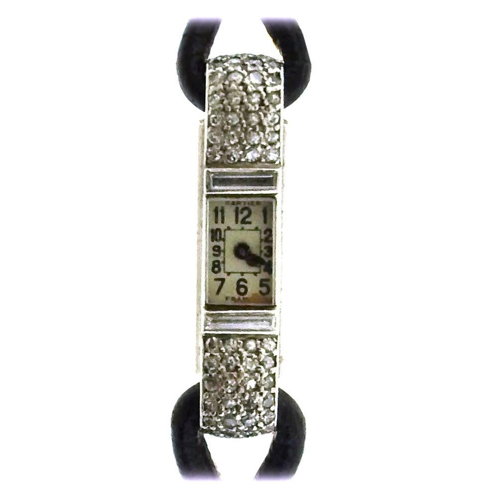 Platinum and 18K yellow gold Cart ier France diamond baguette, made circa 1930, is a fine and rare, small, Art Deco, woman's wristwatch with a cord bracelet,  two diamond-set slides and 18K yellow gold & black enamel curved deployant clasp set