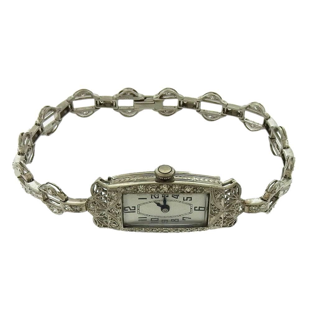 Edwardian lacy filigree platinum and diamond wristwatch is a testimony to the jeweler's art in this circa 1915 wristwatch.  The case measures 14mm x 24mm, bezel set with single-cut diamonds,  with hooded lugs of open platinum filigree attached to an