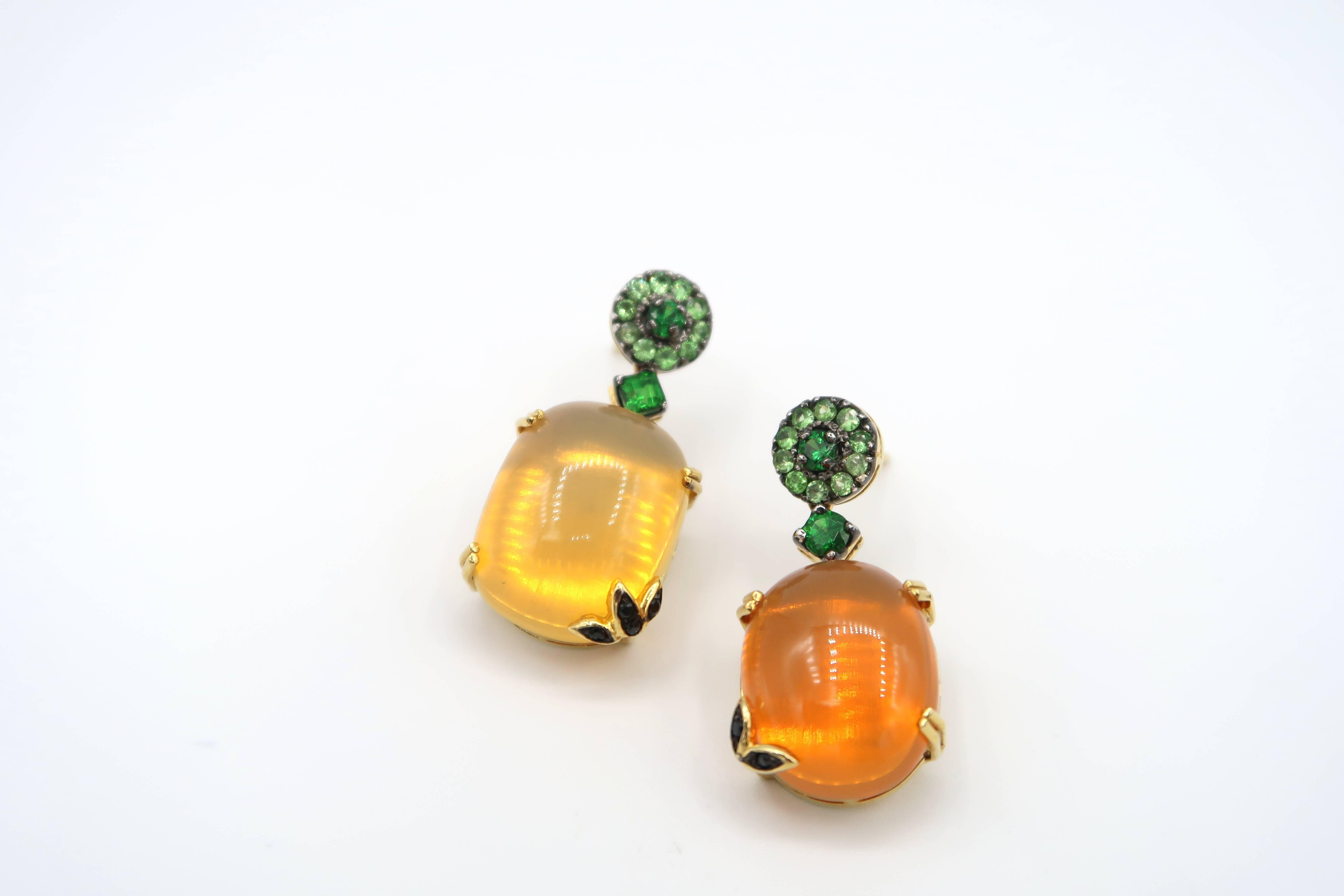 Fire Opal Earrings in 18K Yellow Gold Embellished with Tsavorite and Black Diamond Leaves. Suitable for pierced ears. This piece comes with a complimentary international shipping.

Gold: 9.99g. 18K yellow gold
Fire Opal: 17.32ct.
Tsavorite: