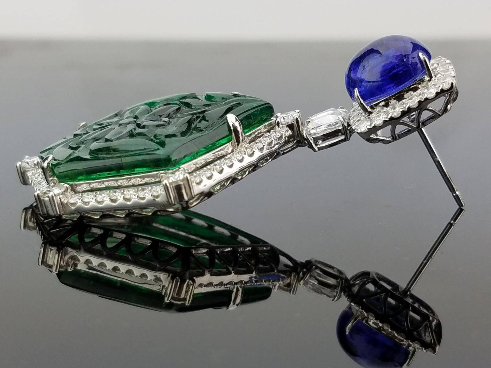 A pair of very unique high quality carved Zambian Emerald and Tanzanite cabochon earrings, with brilliant cut and rose cut Diamonds. 

Stone Details: 
Stone: Zambian Emerald
Cut: Fancy, Carving
Carat Weight: 29.69

Diamond Details:
Cut: Rose cut,