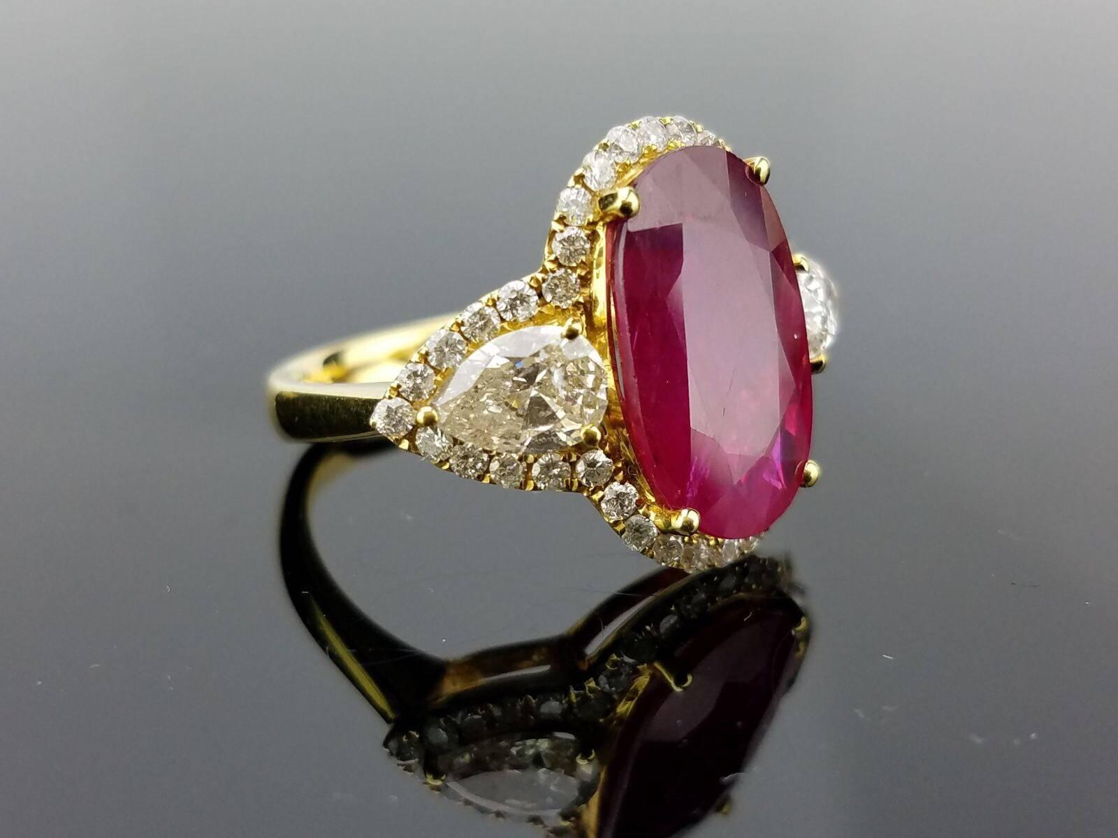 Beautiful Ruby ring with pear shaped white Diamond side stones, and brilliant cut Diamond. All set in 18K yellow gold.

Stone Details:  
Stone: Mozambique Ruby 
Cut: Oval
Carat Weight: 5.87 Carat  

Diamond Details: 
Cut: Brilliant cut / Pear