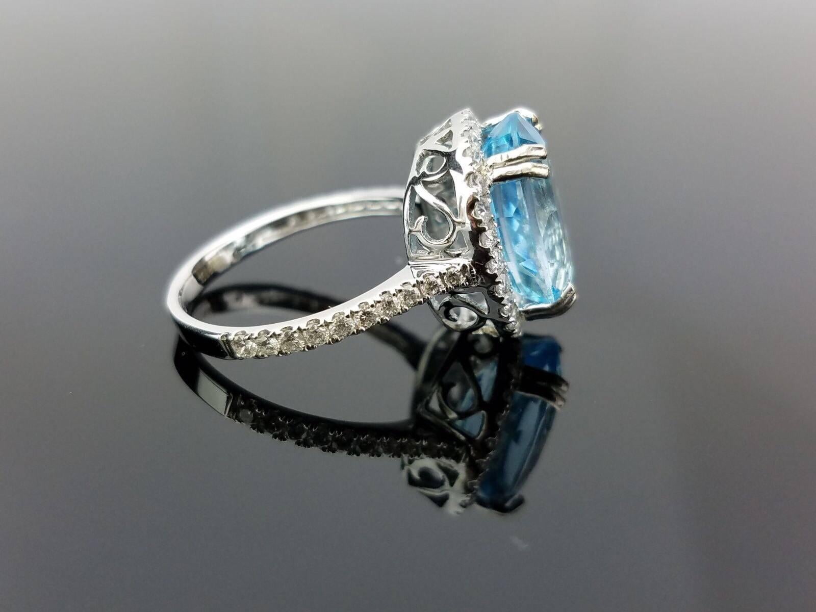 Magnifique Topaze bleue avec un halo de diamants serti sur un anneau d'or blanc 18K

Détails de la pierre centrale :  
Pierre : Topaze bleue
Coupe : Ovale
Poids : 6,28 carats

Détails du diamant :
Taille : Brilliante (ronde) 
Poids total en carats :