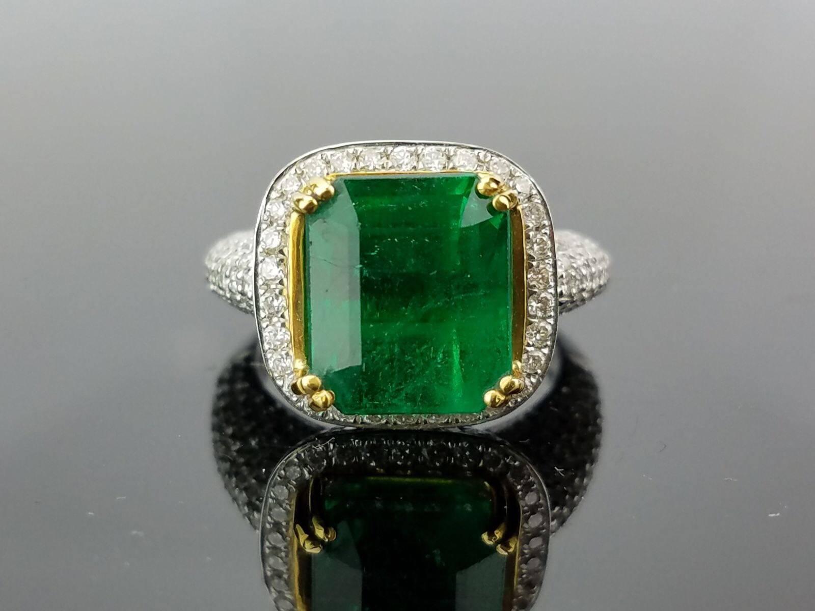 A classic cocktail ring, with a lustrous emerald cut Zambian emerald  sorrounded with White Diamonds, all set 18K white gold. 

Stone Details: 
Stone: Emerald
Carat Weight: 6.24 Carat

Diamond Details:
Total Carat Weight: 1.73 carat
Quality: VS/SI ,