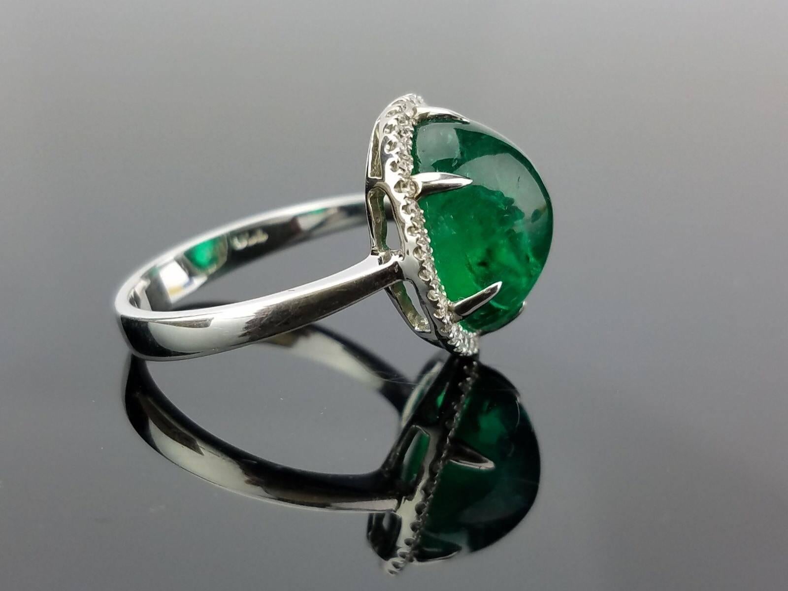 An elegant cocktail ring using a beautiful Emerald Cabochon centre stone surrounded with White Diamond, all set in 18K white gold. 

Stone Details: 
Stone: Emerald
Carat Weight: 7.46 carats

Diamond Details: 
Total Carat Weight: 0.32 carat
Quality: