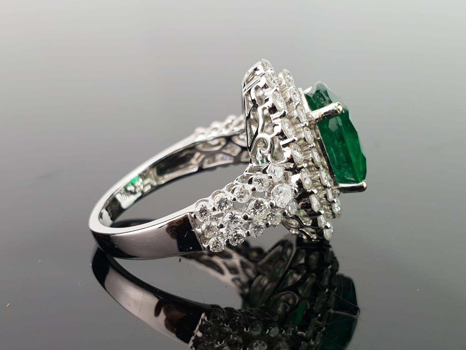 An elegant and simple cocktail ring using a 3.74 carat round cut Zambian Emerald centre stone, with 1.78 carat of brilliant cut diamonds sorrounding it, all set in 18K white and gold. Currently a ring size US 6, but we can resize the ring for you