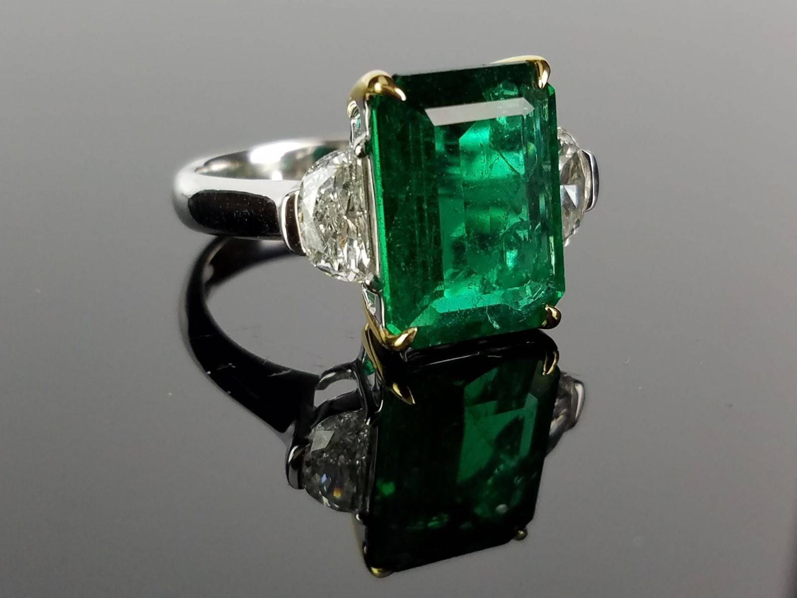 Classic Emerald ring with 2 half-moon Diamond side stones.

Center Stone Details: 
Stone: ZambianEmerald
Cut: Emerald Cut
Weight: 4.99 carat 

Side Diamond Details: 
Cut: Half moon
Total Carat Weight: 0.83 carat 
Quality: VS2, H/I 

18K Gold: 5.22