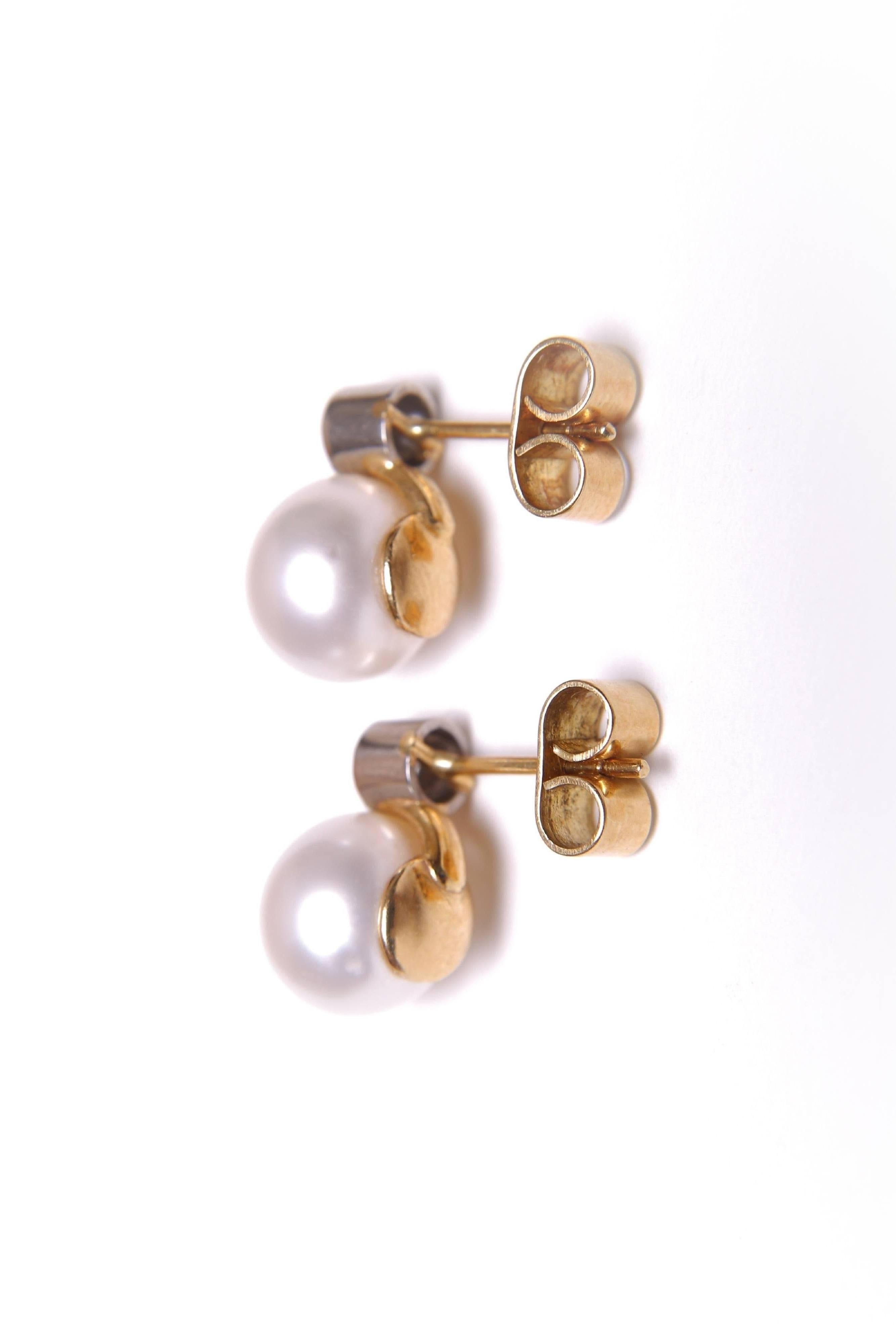 A pair of diamond and cultured pearl two stone stone earrings. The two round brilliant cut diamonds weigh a total of approximately 0.50 carats and the two cultured pearls approxiamately are 10mm diameter each. The metal is 18 carat yellow and white