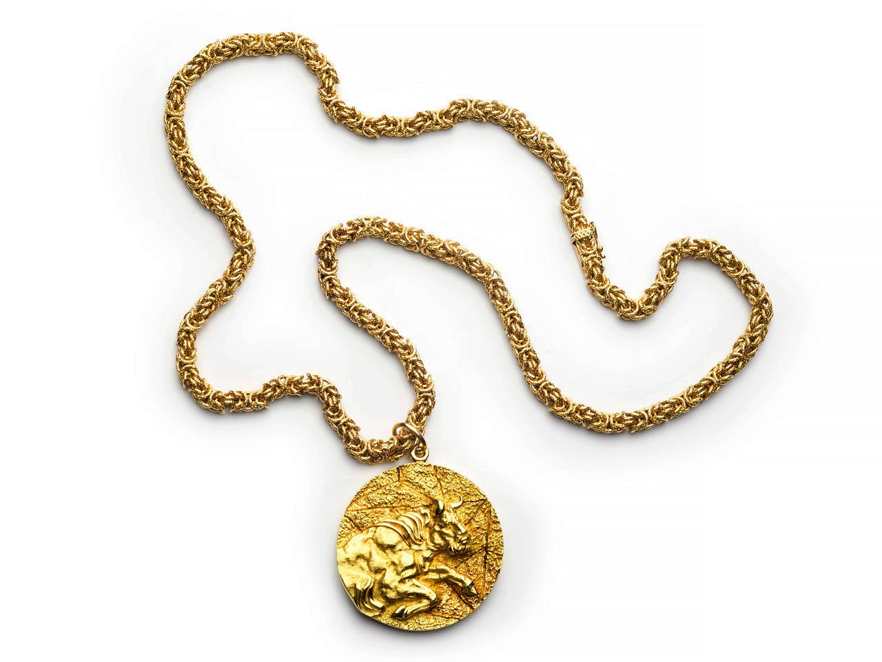 18k gold woven chain suspending a circular embossed pendant with Taurus the bull in high relief. Maker's mark and 18k mark.